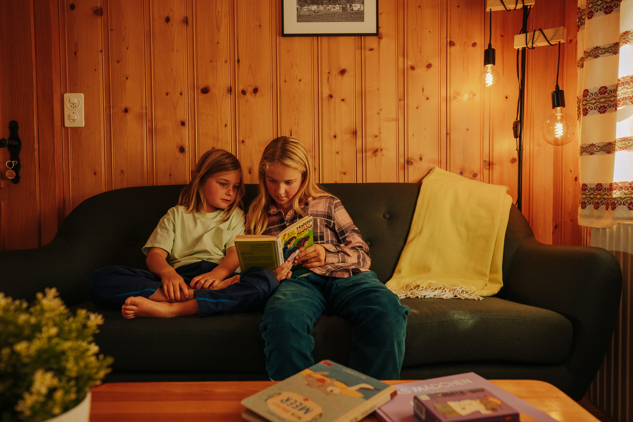 zwei Kinder auf einem Sofa lesen ein Buch