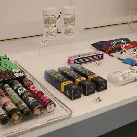 Close-up of cannabis product offerings at Cannavine San Francisco, including branded vapes, edibles, and tinctures neatly arranged on a counter with visible price tags.