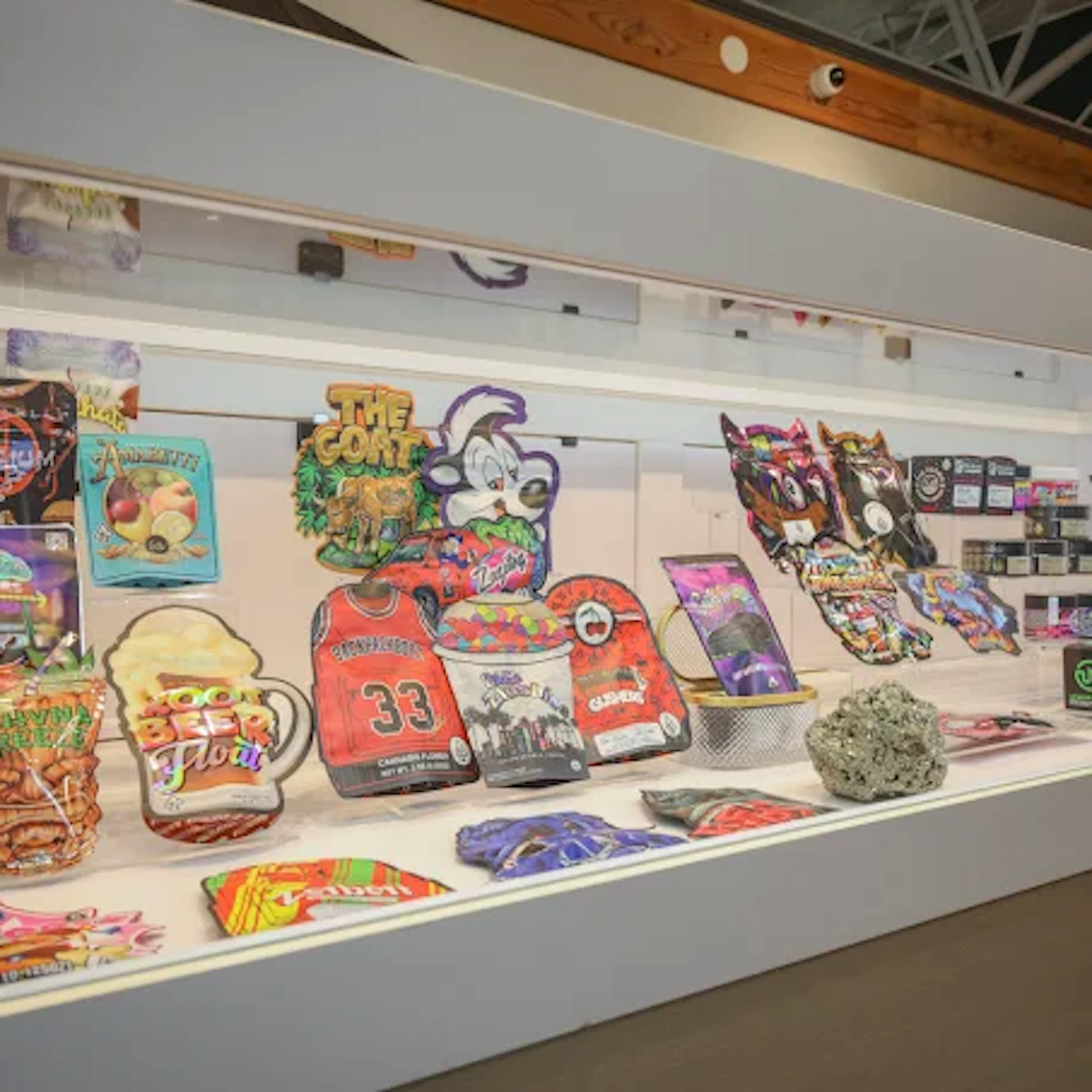 Colorful, branded cannabis product packaging displayed inside a well-lit counter case at Cannavine Ukiah. Includes edibles, flower pouches, concentrates, and jars, with a staff member visible in the background.