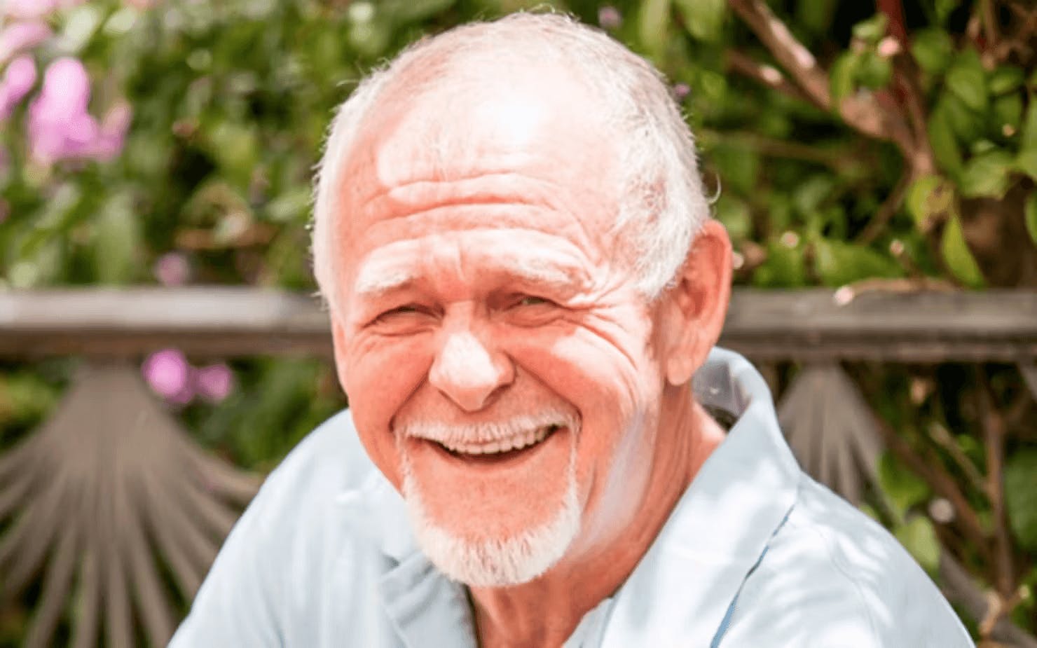 Image of Rick Simpson wearing a light blue shirt outdoors with greenery in the background
