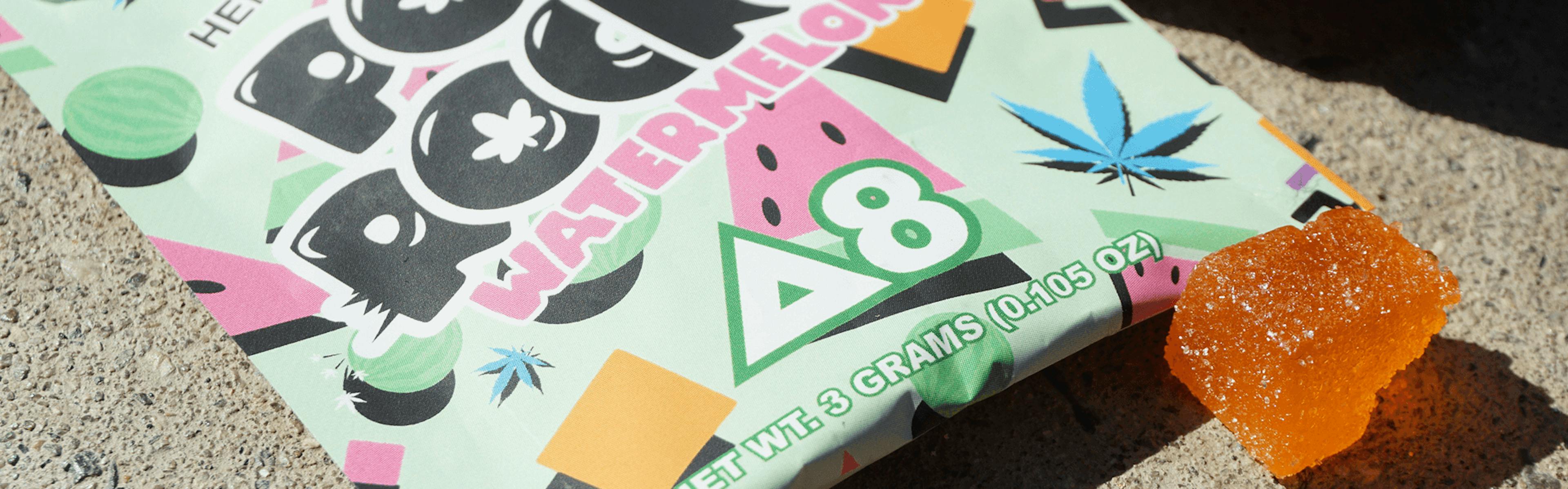 Delta-8 THC Pot Rocks watermelon candy with orange cannabis gummies on concrete surface