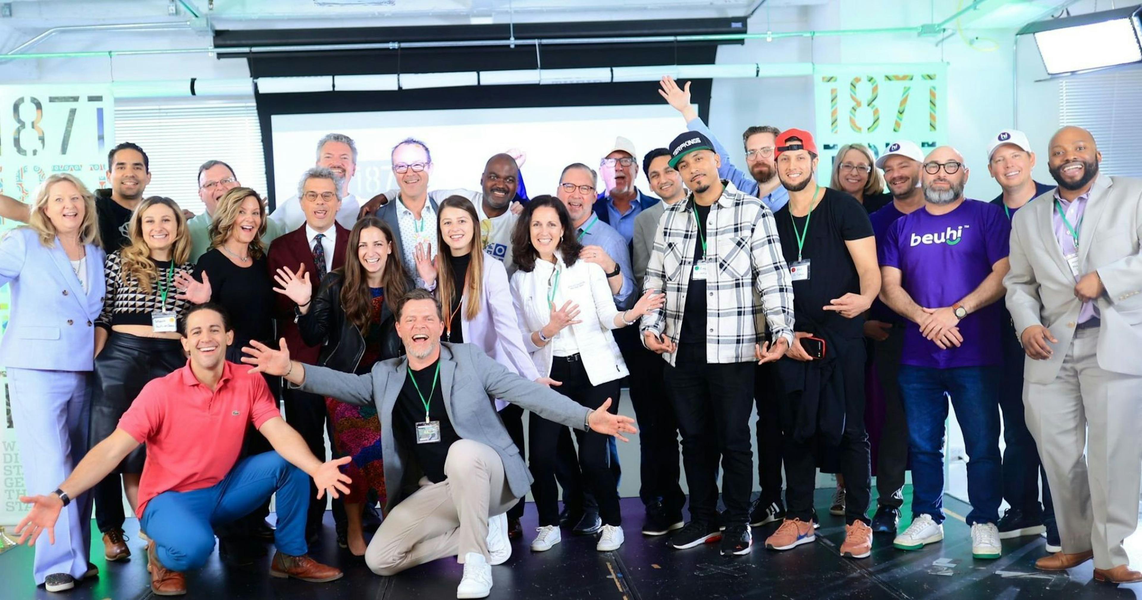 A group of smiling individuals celebrating on stage at the 1871 Incubator closing ceremony