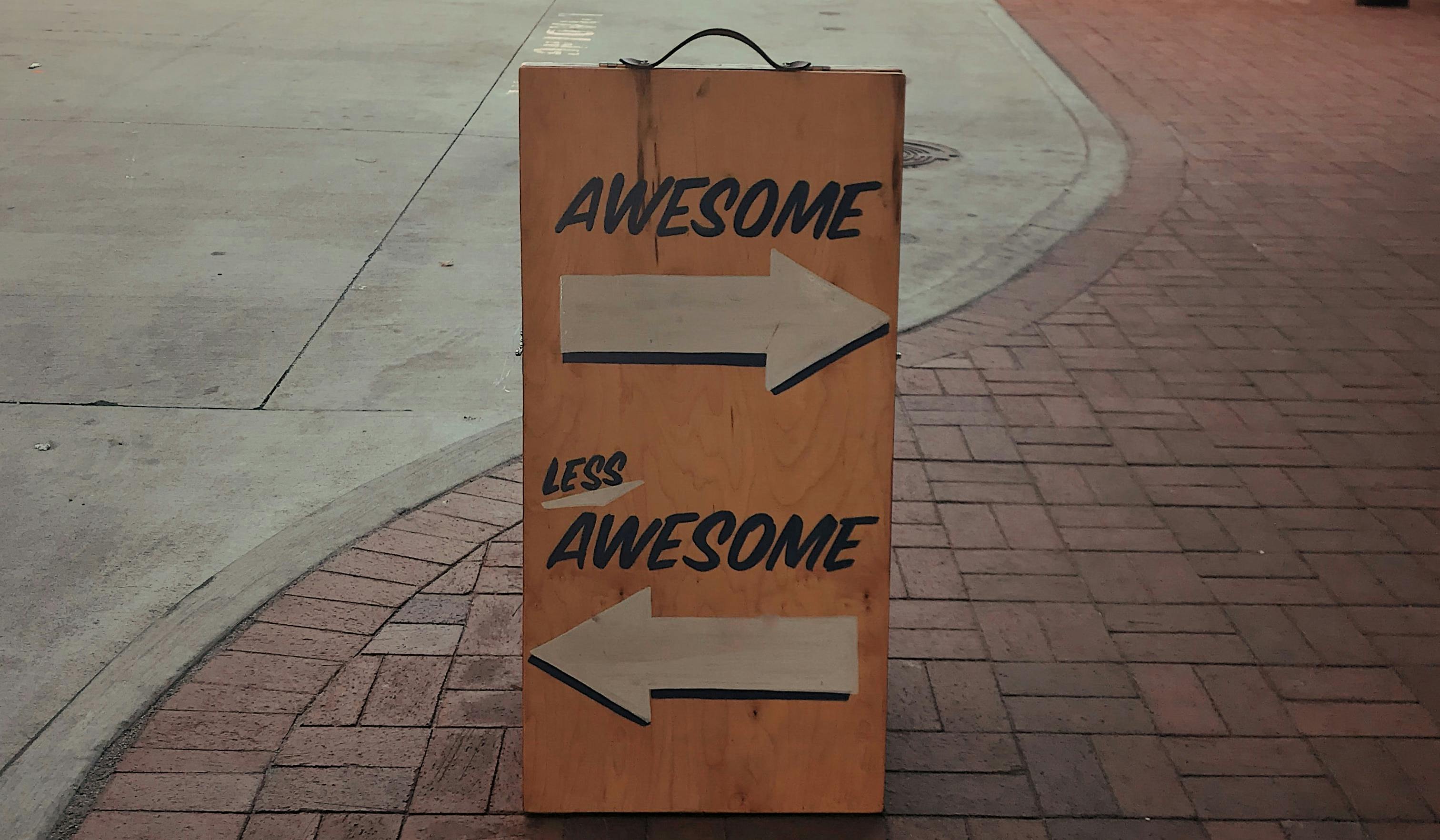 A sign saying "Awesome" with an arrow pointing right, and another arrow pointing left saying "Less Awesome".