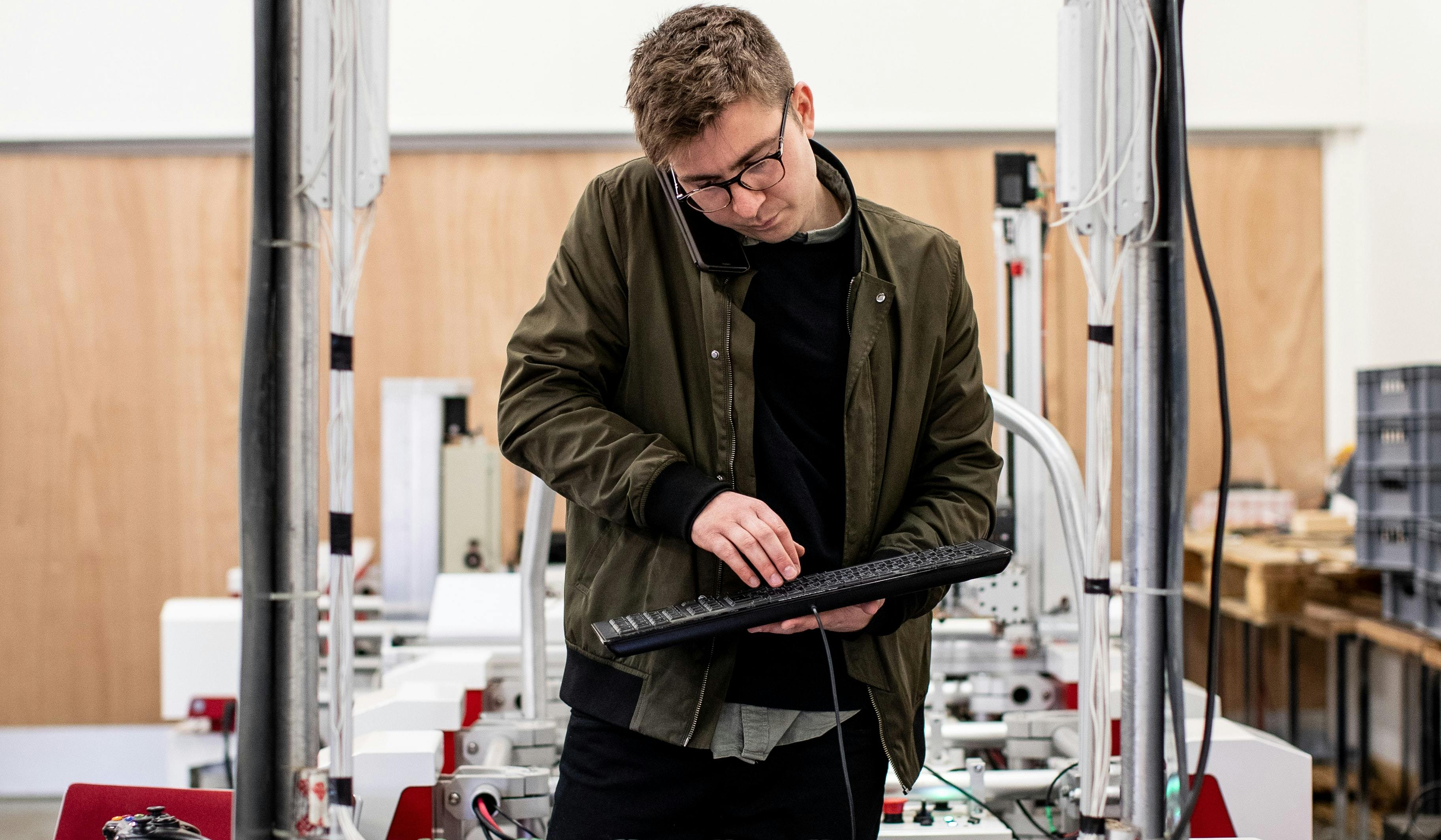 A man using a keyboard whilst on the phone.