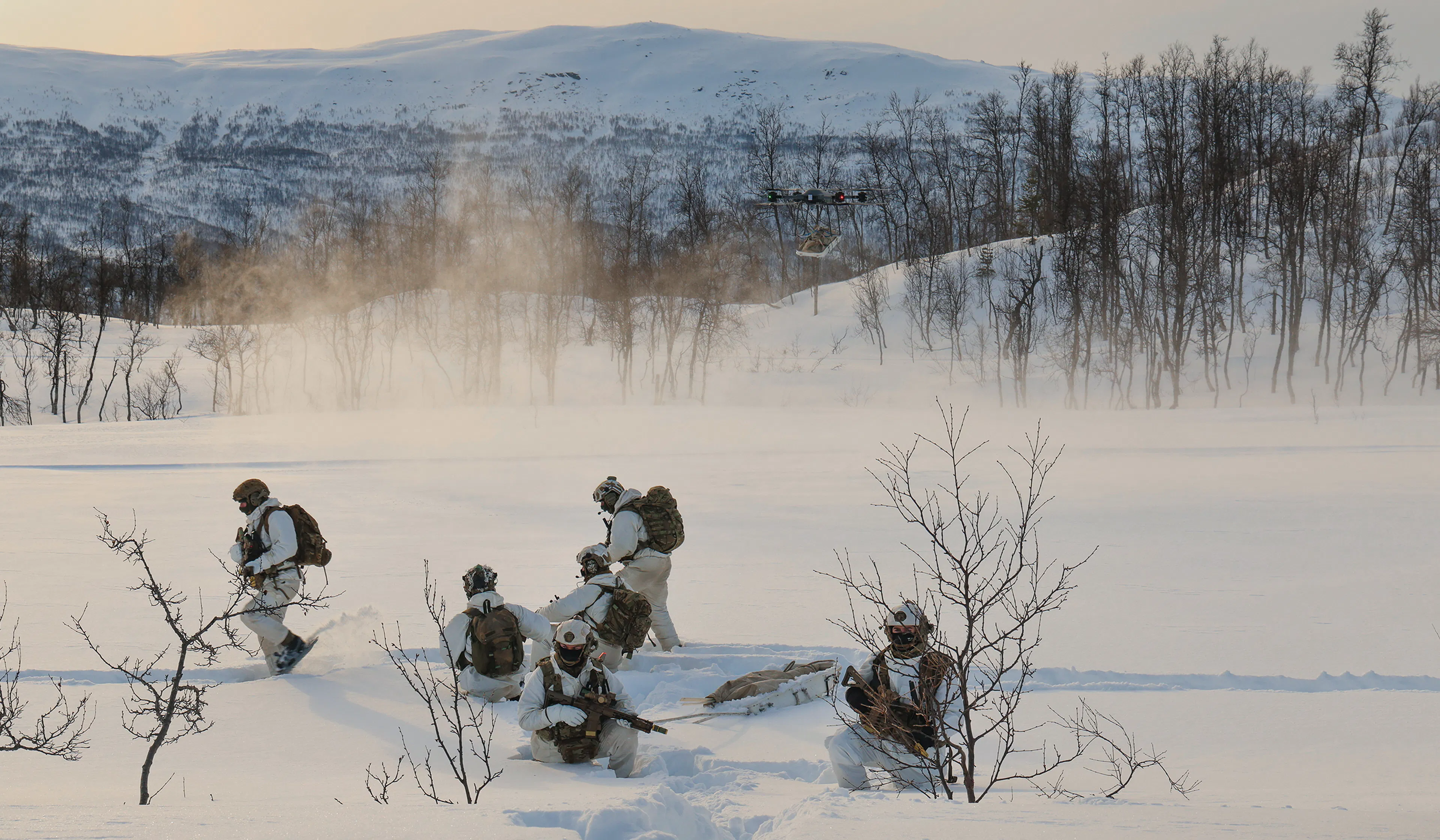 Royal Marines operating a heavy-lift drone in deep snow during cold weather training in Norway.