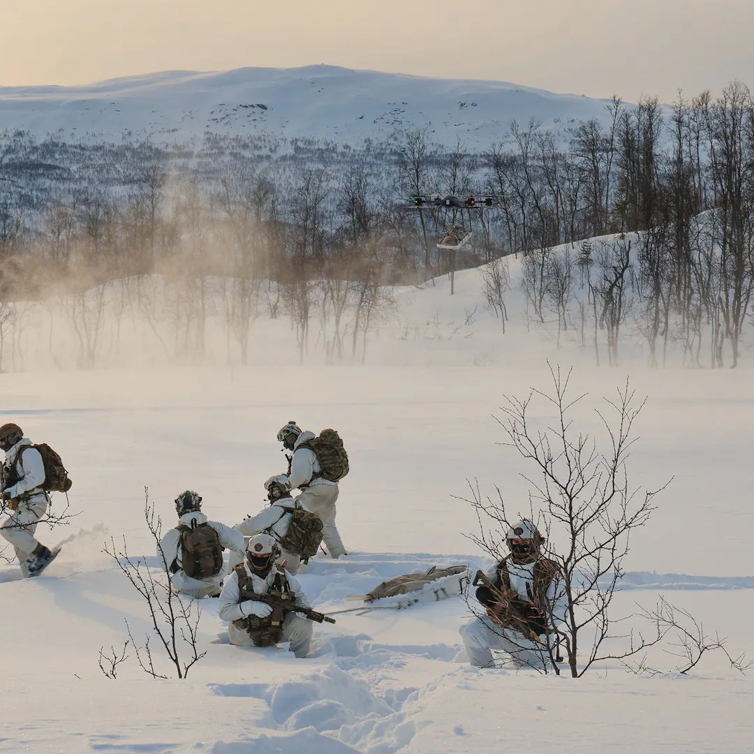 Royal Marines operating a heavy-lift drone in deep snow during cold weather training in Norway.