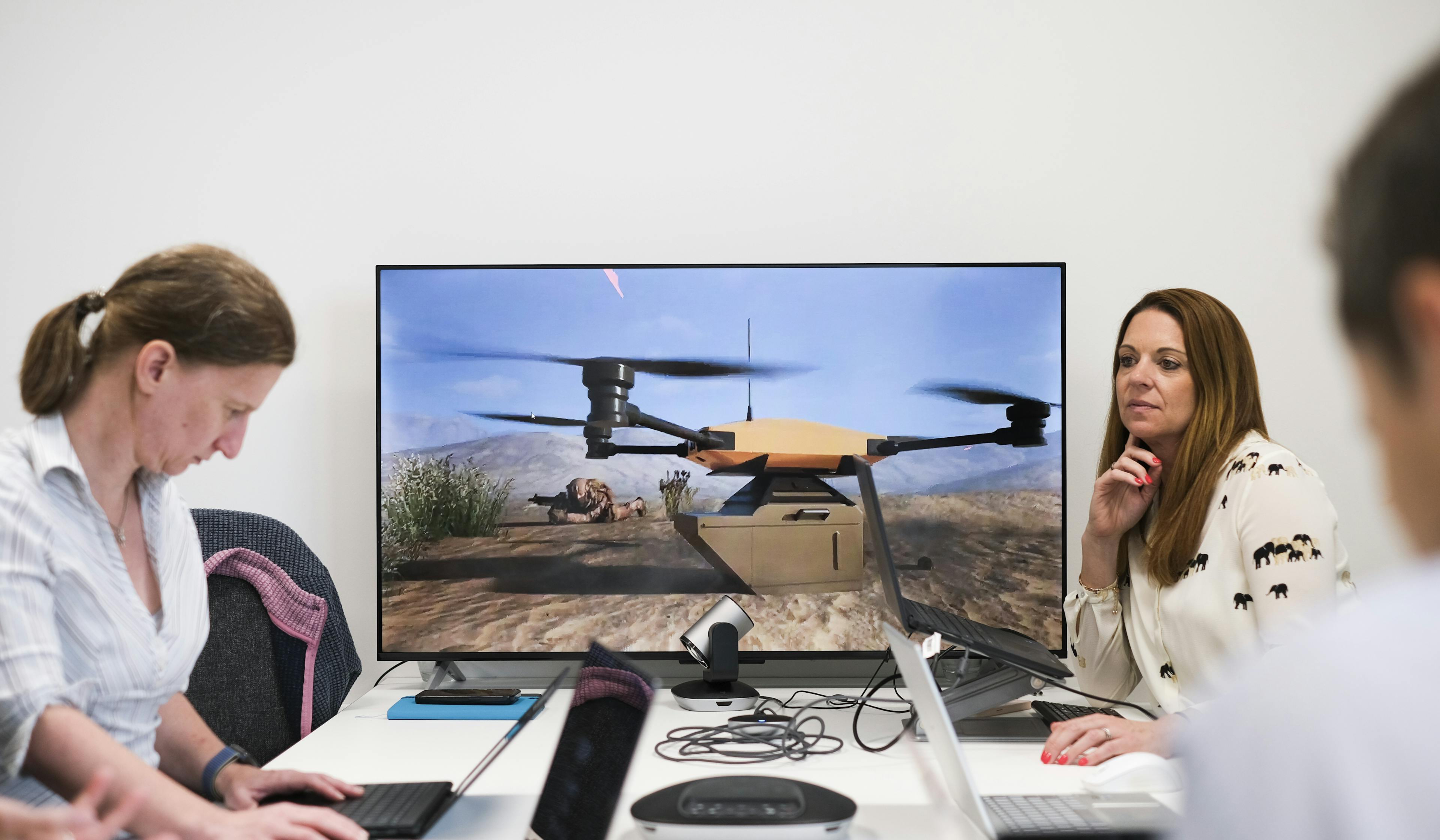 The team in front of a screen with a CGI animated drone on it showing the TB2 DROPS system