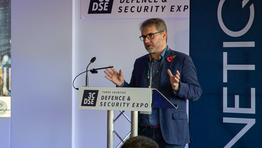 James Peddell speaking on stage at 3CDSE