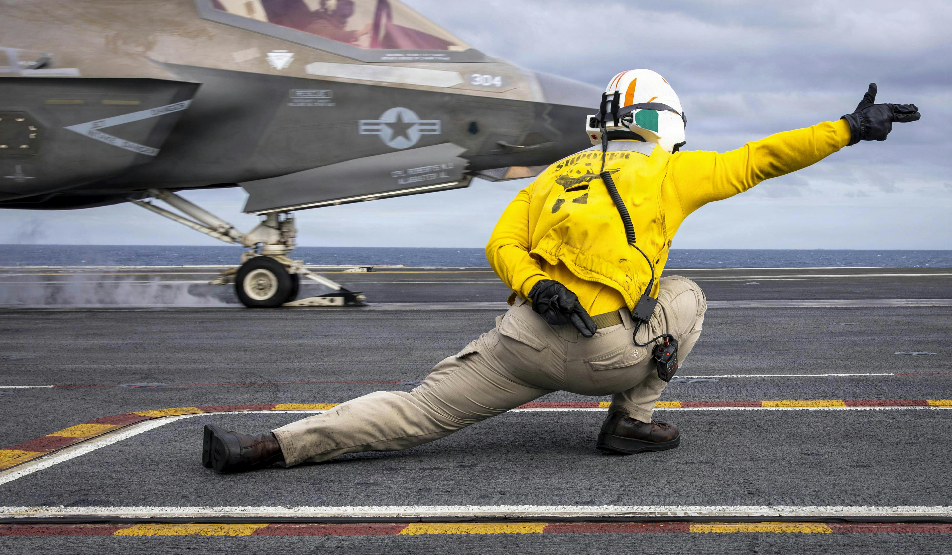 Navy Lt. Cmdr. Jarrett Walden signals an F-35C Lightning II as it launches from the USS Abraham Lincoln in the South China Sea, Jan. 4, 2026.