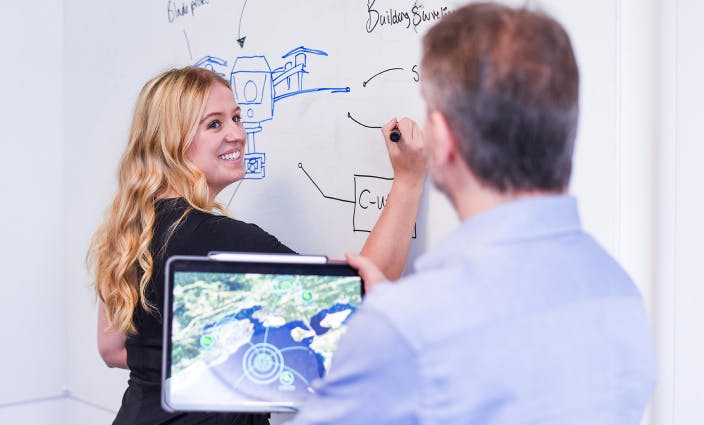 Two Canny Comms team members working at a whiteboard.