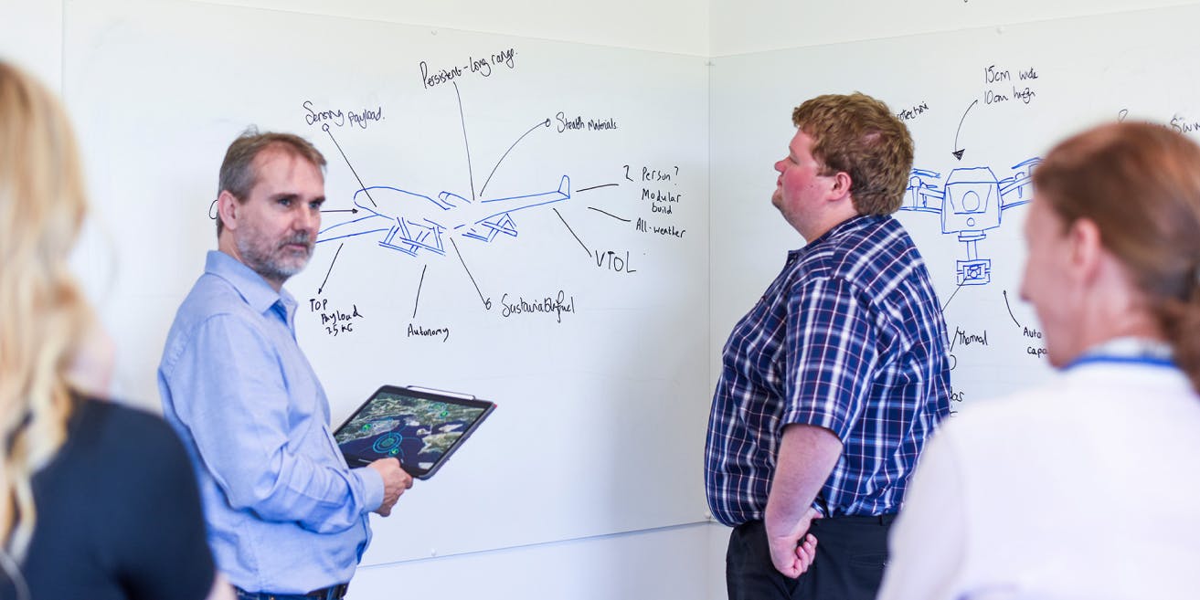 Canny Comms team members working at a whiteboard.