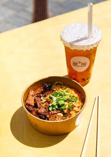 a rice bowl with tofu made by juk pou with bubble tea beside it on a bright table