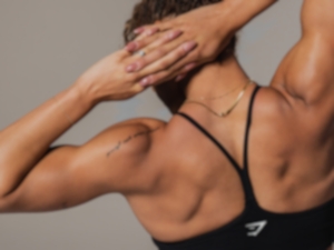 Woman wearing black sports bra while flexing back muscles. 