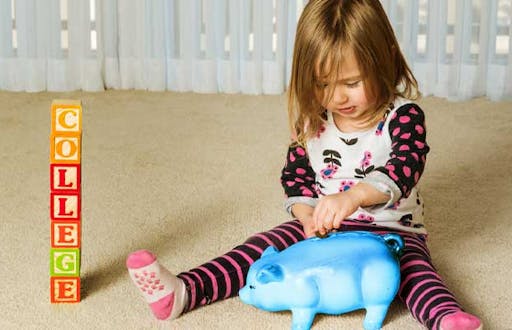 A child putting college savings inside of a piggy bank.