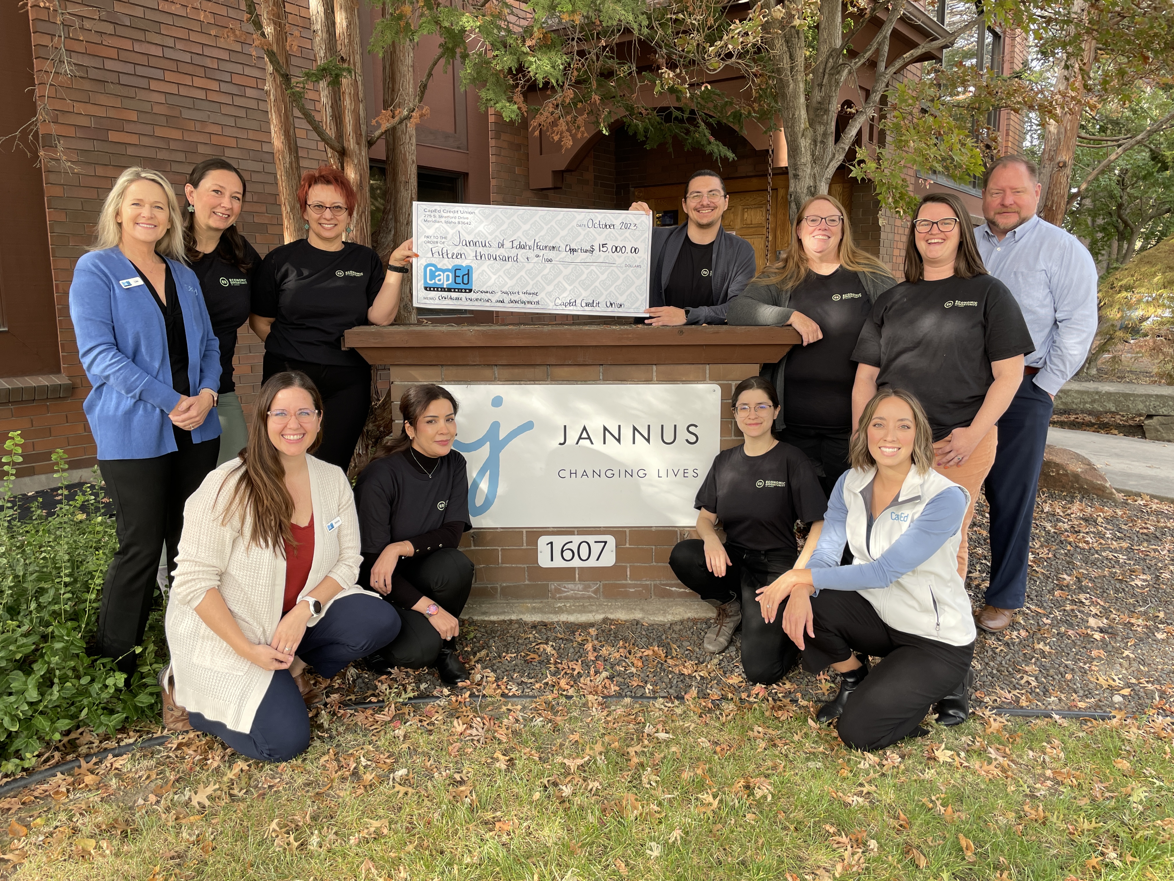 Employees from CapEd Credit Union and Economic Opportunity by Jannus in front of the Jannus sign outside with a large check written to Jannus in the amount of $15,000.