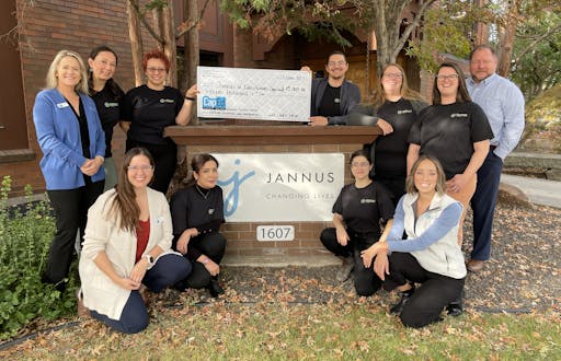 Employees from CapEd Credit Union and Economic Opportunity by Jannus in front of the Jannus sign outside with a large check written to Jannus in the amount of $15,000.