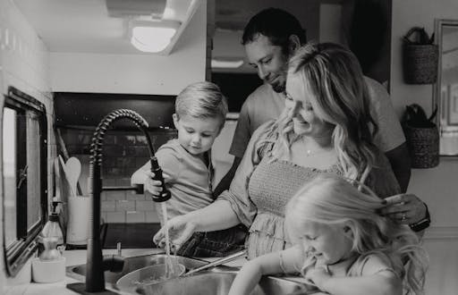 Jaimie Appel, her son, daughter and husband gathered around their sink in their newly renovated motorhome kitchen. Photo by Natalia Meyerhoffer.