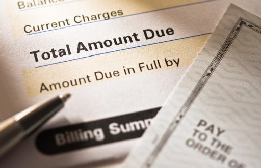 Paper billing statement, a pen and a bank check.