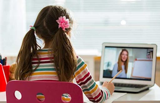 Student being taught in a digital environment with a teacher on a laptop screen.