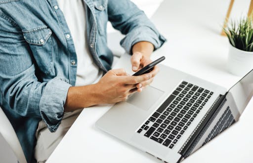 Person using their cell phone and laptop to enroll in CapEd eBanking.