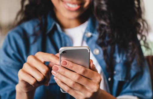 Woman smiling and making a selection on her cell phone.