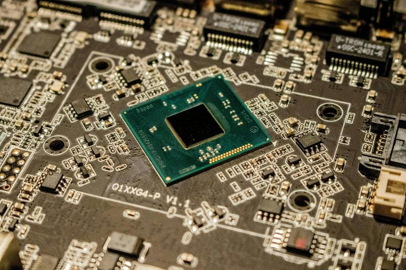 Central green chip on circuit board with intricate components and pathways.
