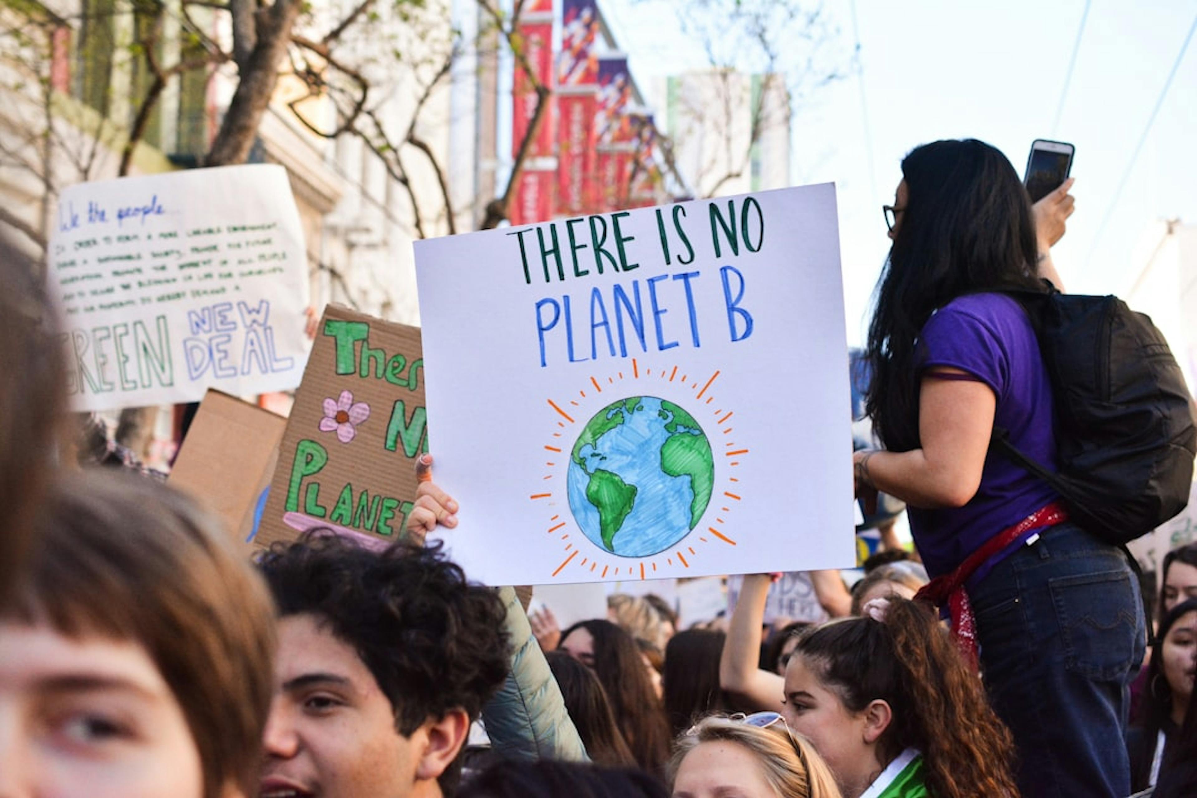 people holding a poster of Earth with a  environmentally-conscious message, symbolising growing awareness and action towards sustainable coffee farming practices