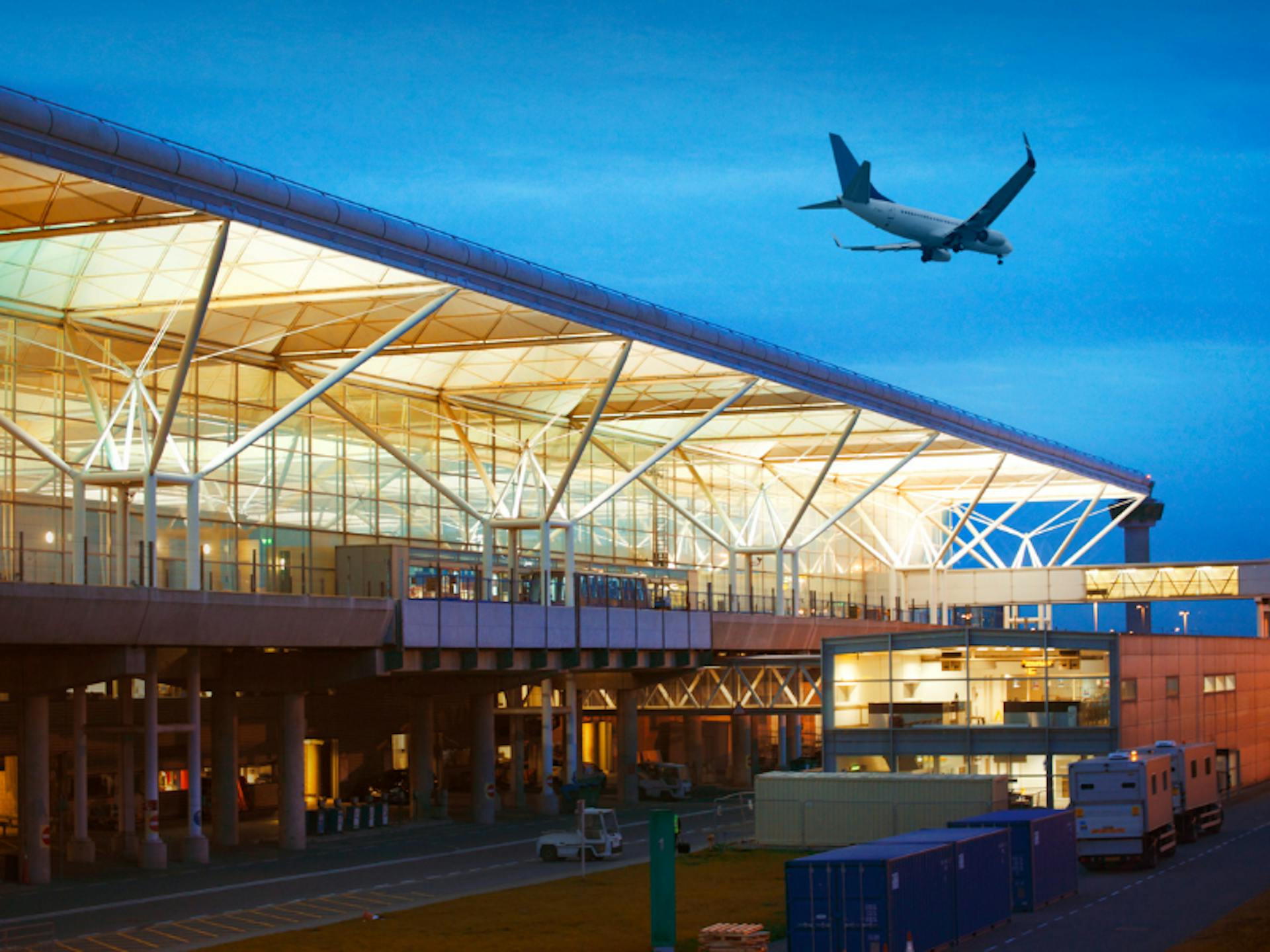 Airport with a plane flying above at night