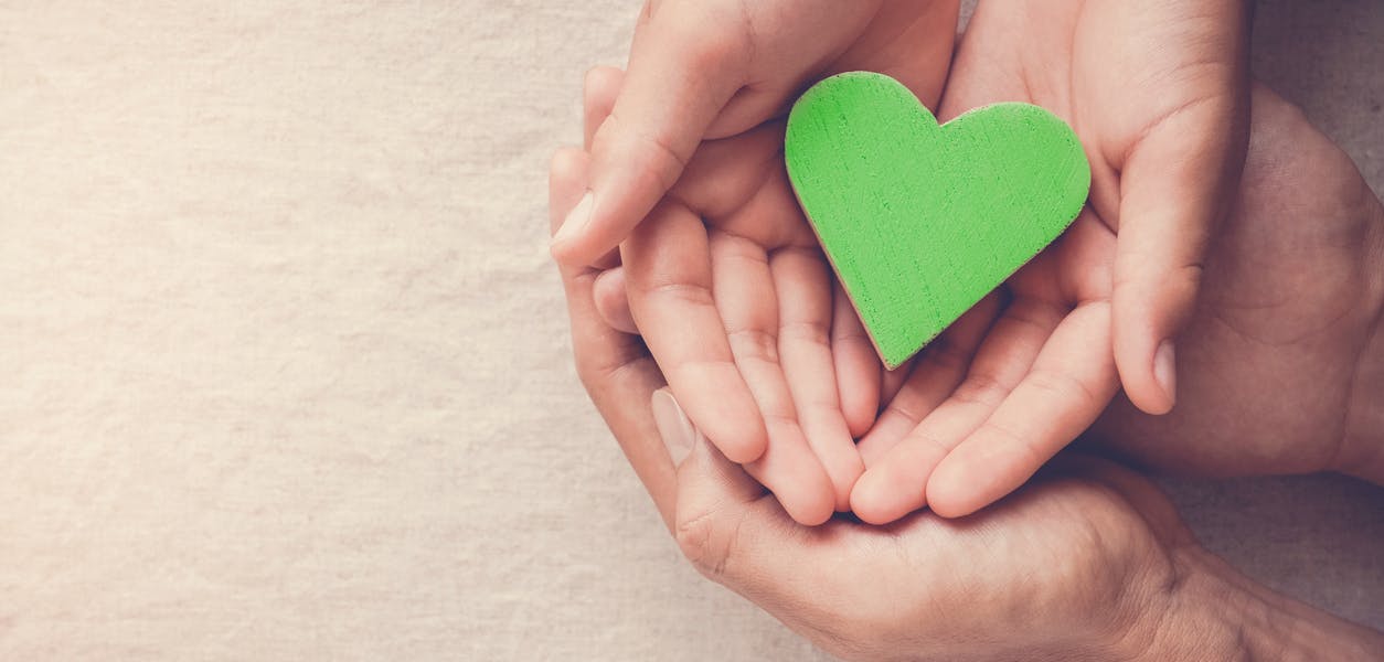 Volwassenen en een kind houden een groen hart vast