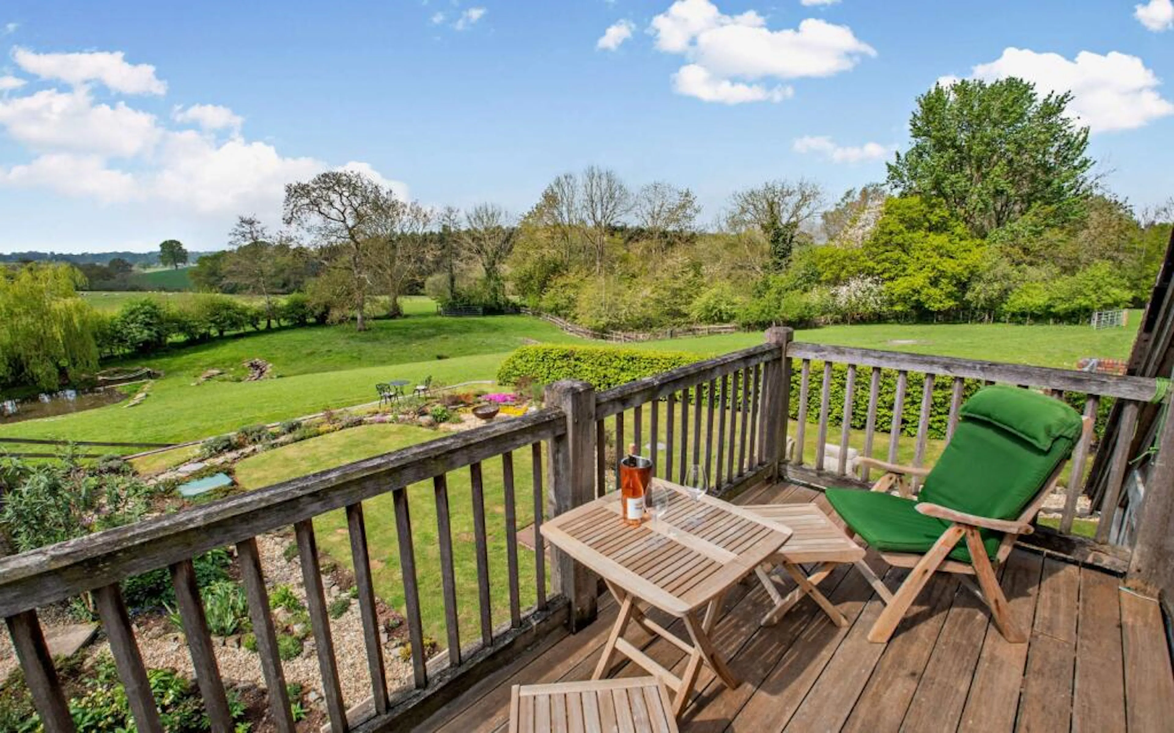 An oak framed balcony on a traditional stone cottage overlooking a large garden