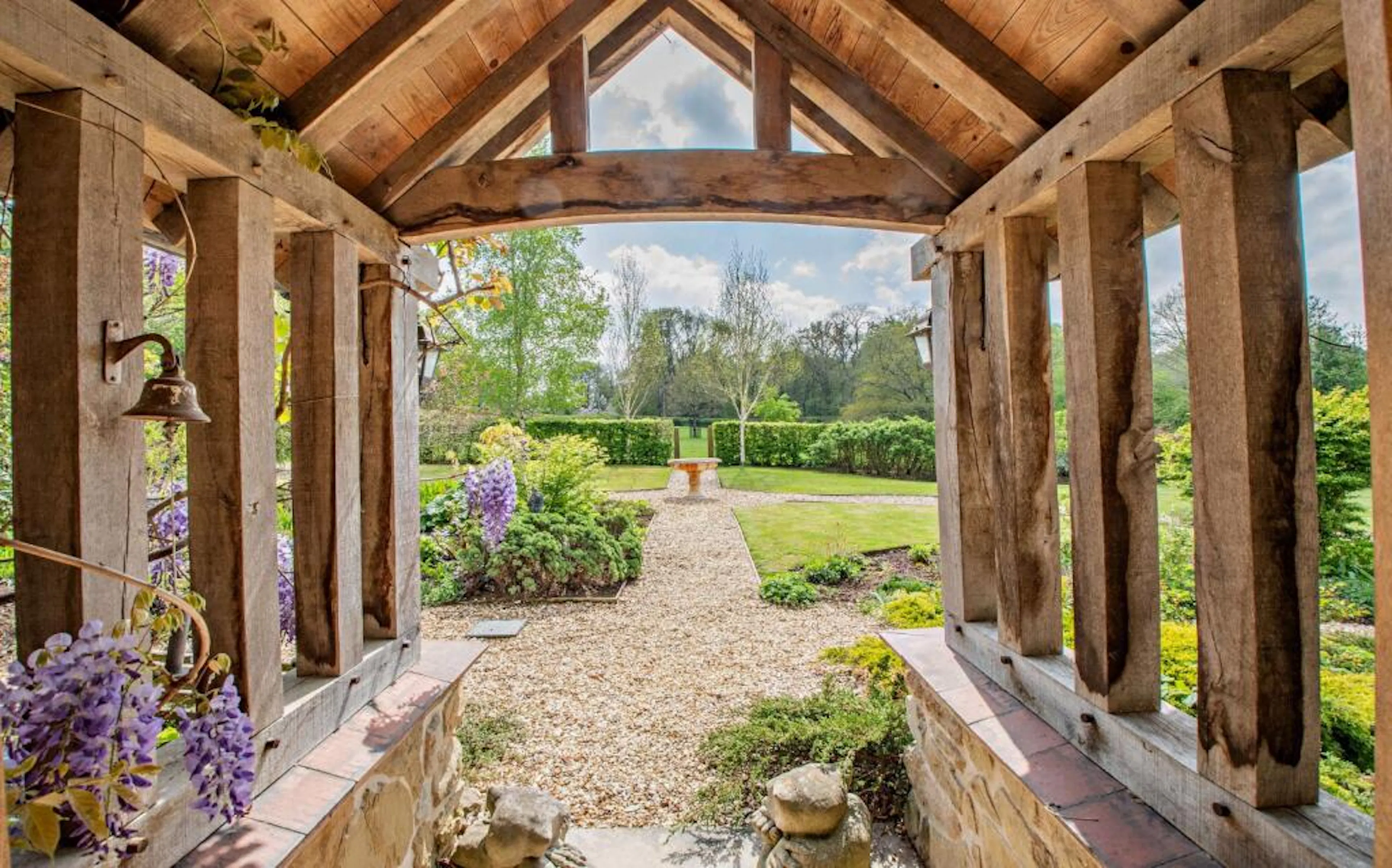 Inside an oak framed porch on a traditional stone cottage, looking out into a landscaped garden