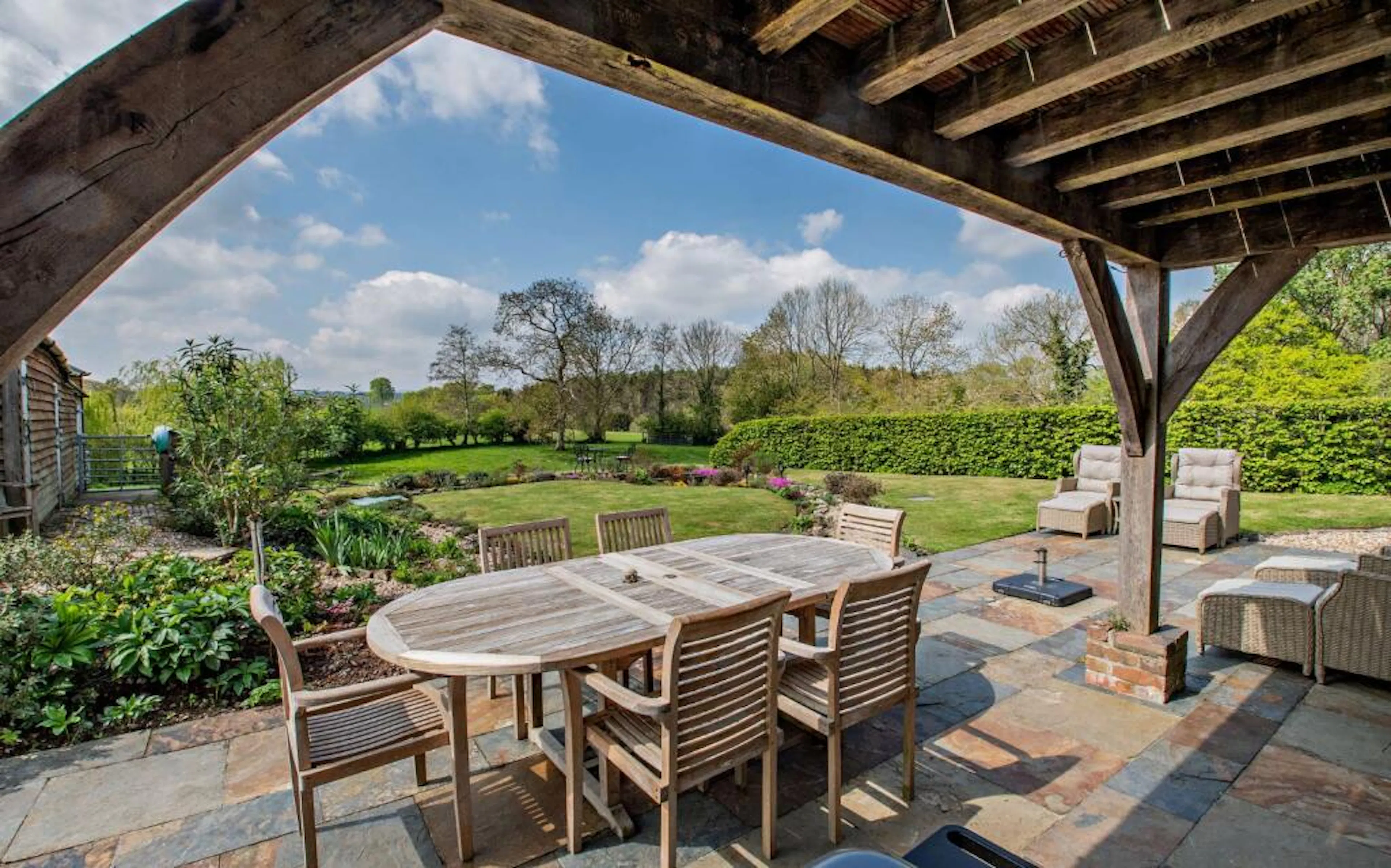 An oak framed veranda on a traditional stone cottage overlooking a large garden