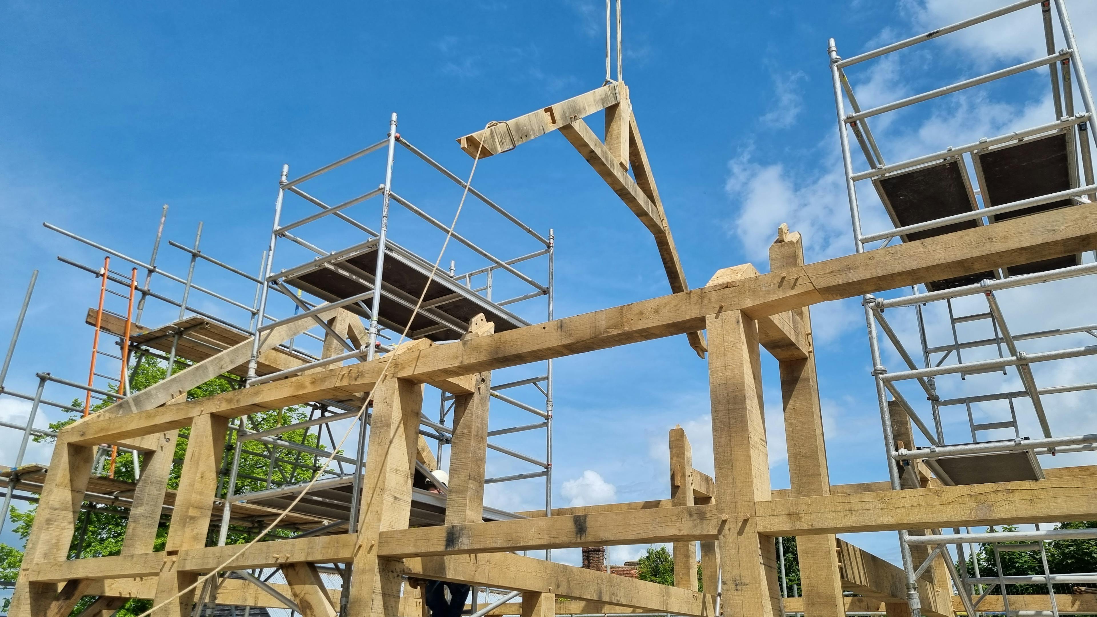A truss being lowered by a crane during installation of an oak frame home