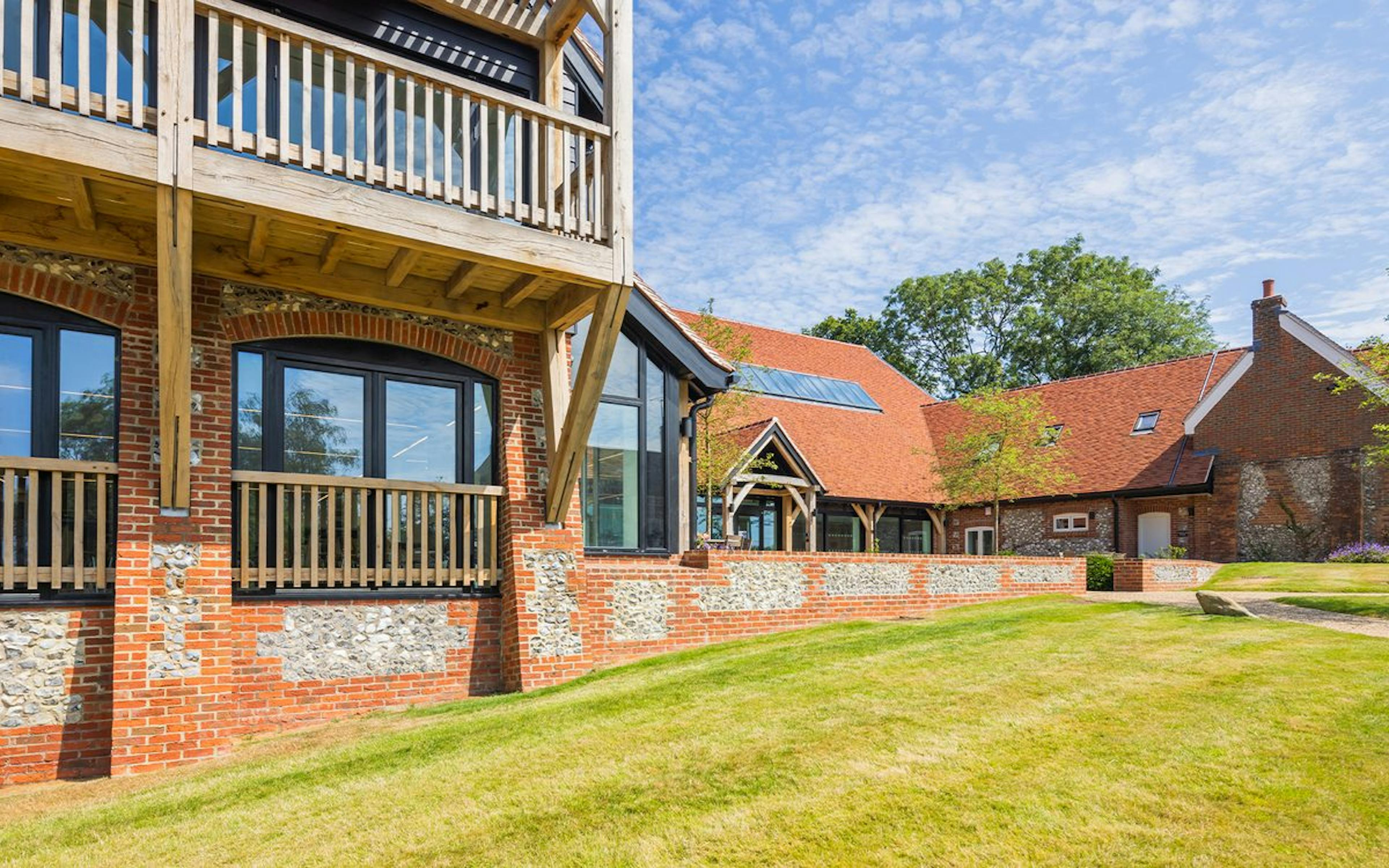 A large brick and flint building with a large oak balcony on the front