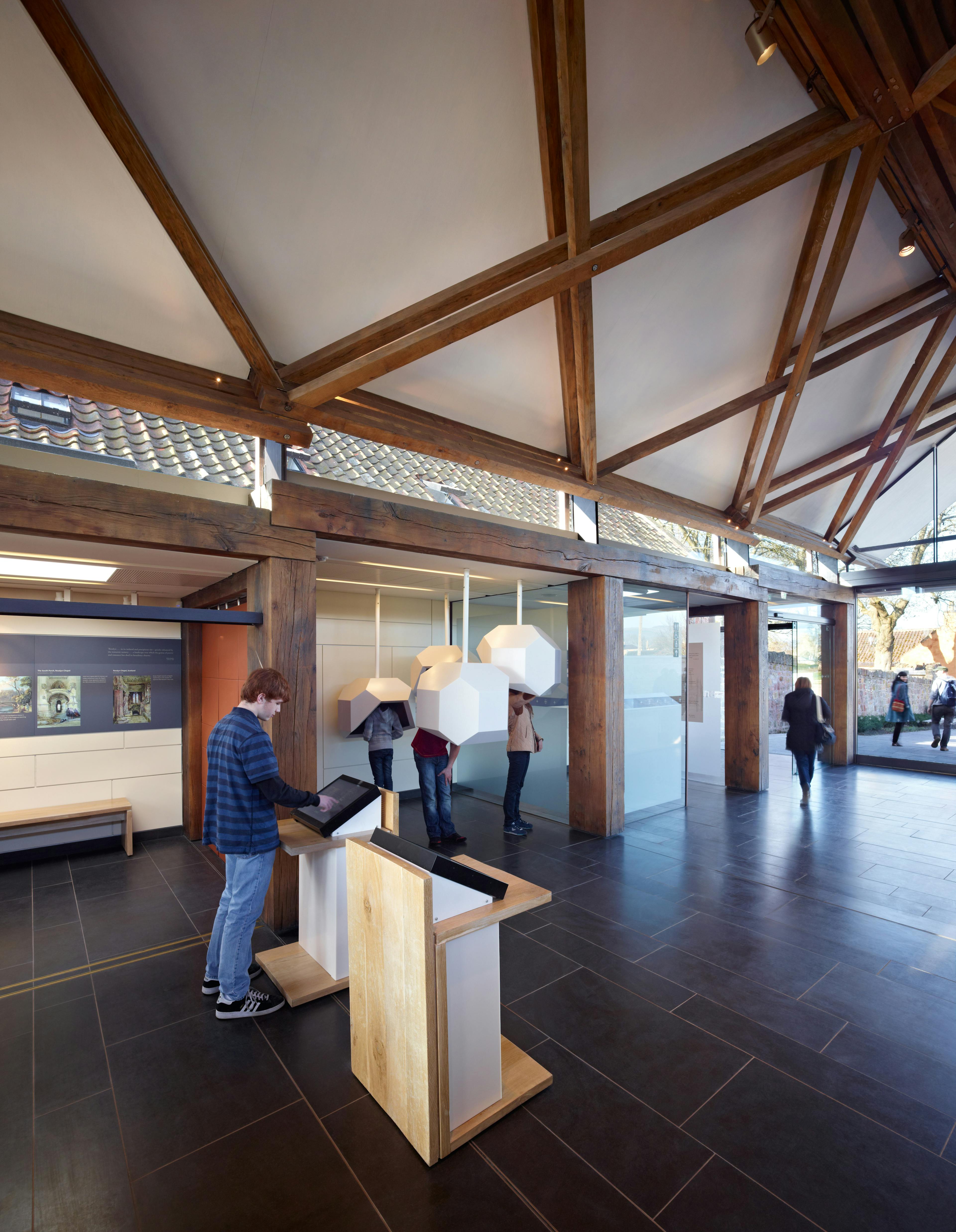 A visitors centre at a chapel in Scotland with scissor braced slender timbers create a criss-crossed timber framed roof structure