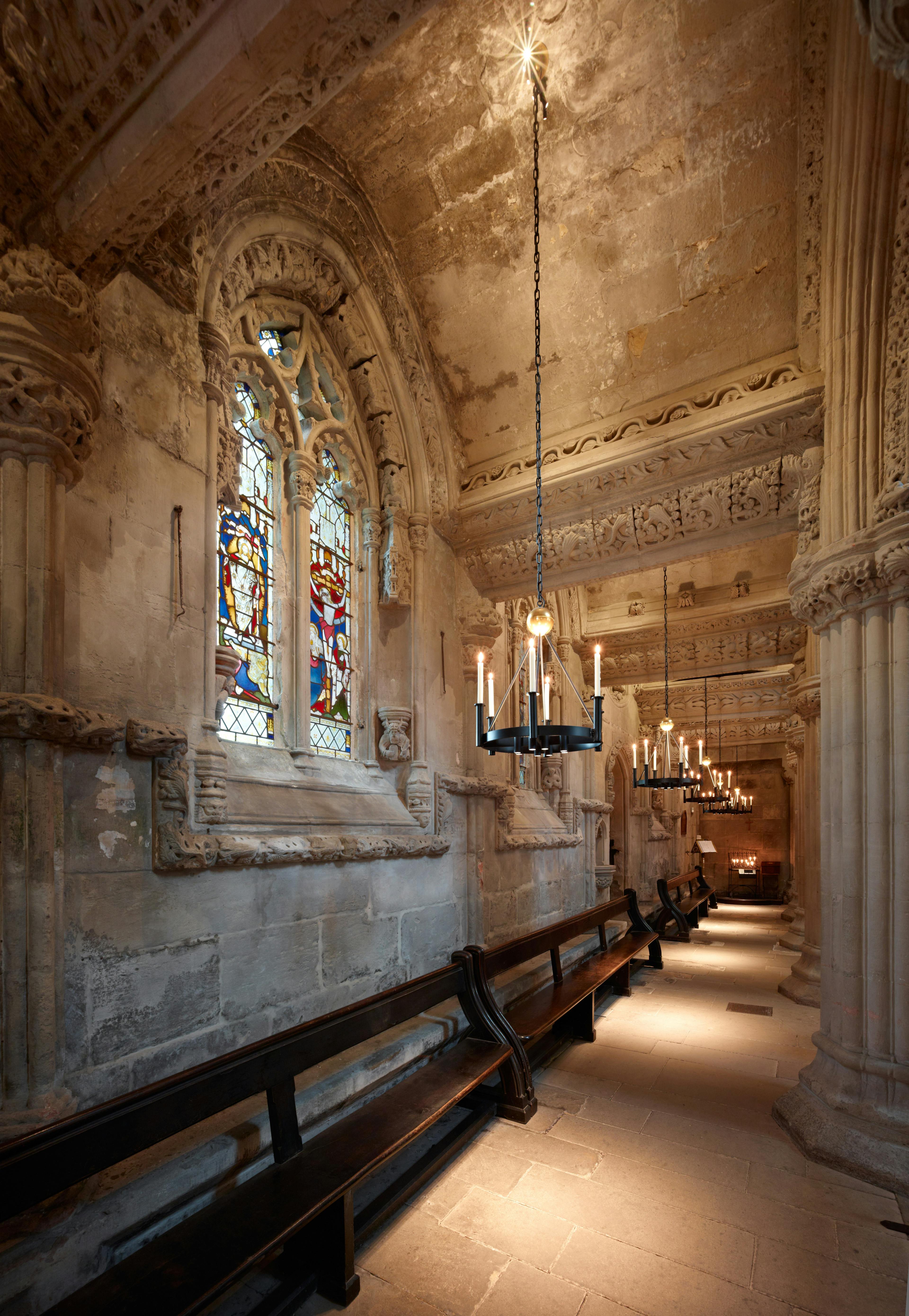 Interior view of Rosslyn Chapel, highlighting its ornate stone carvings, stained glass windows, and vaulted ceiling