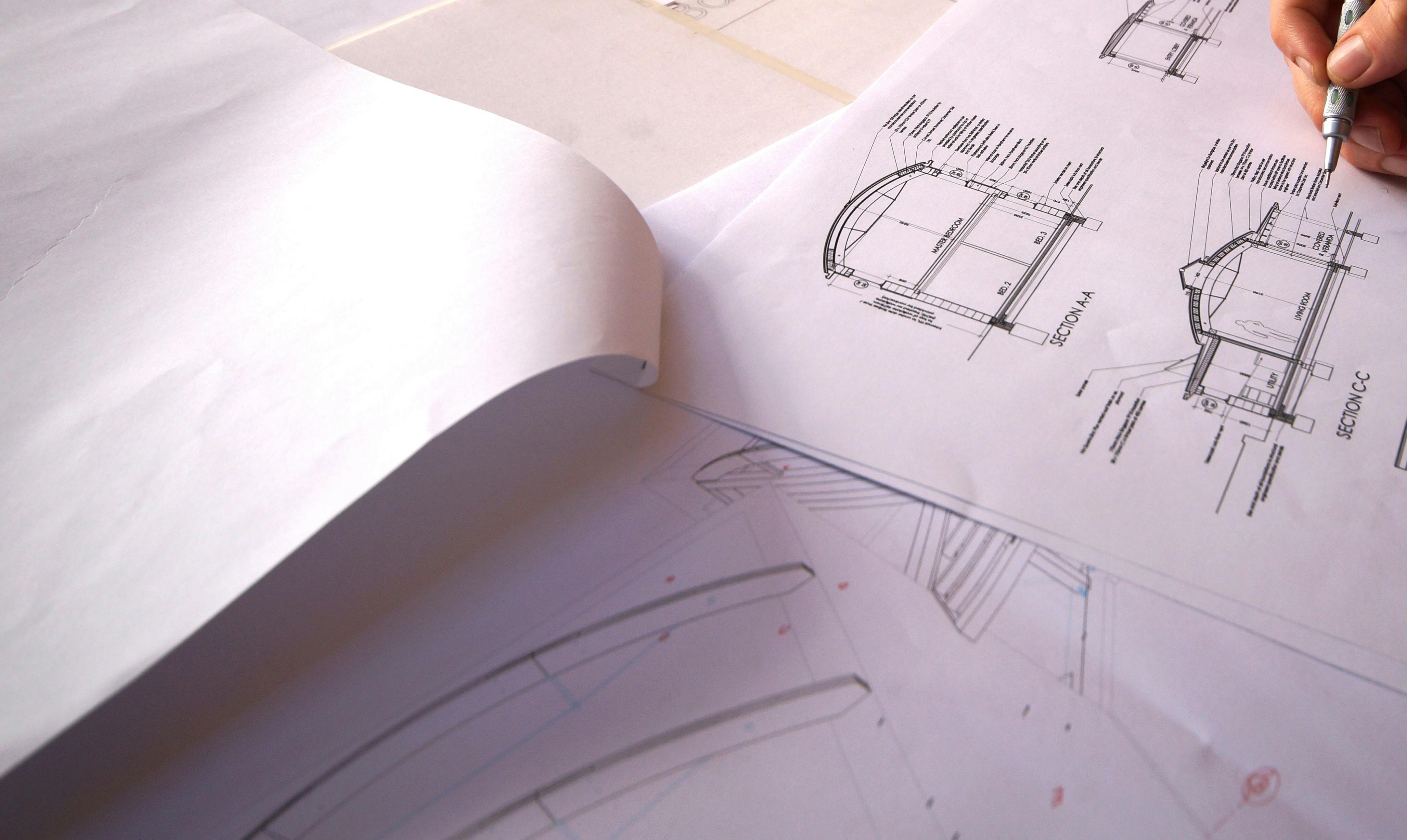 An architect with pen drawing on floorplans for a building