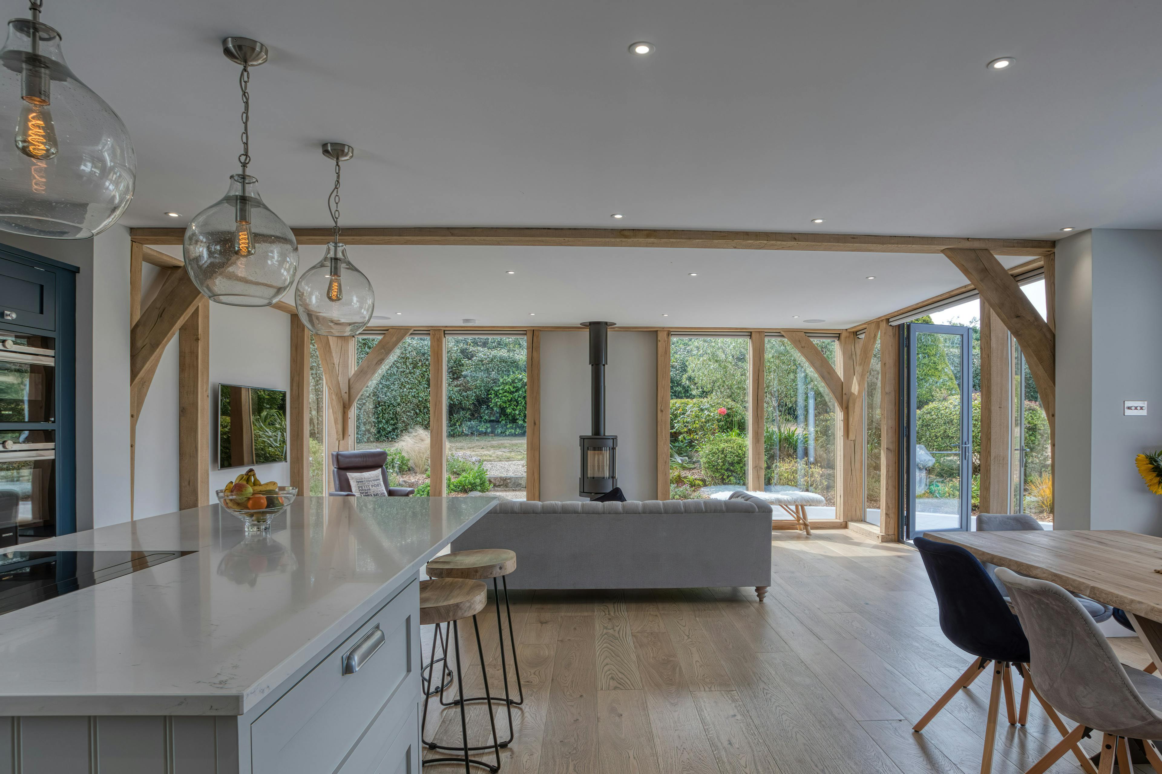 Interior view of an open-plan oak-framed extension with sitting, dining and kitchen areas