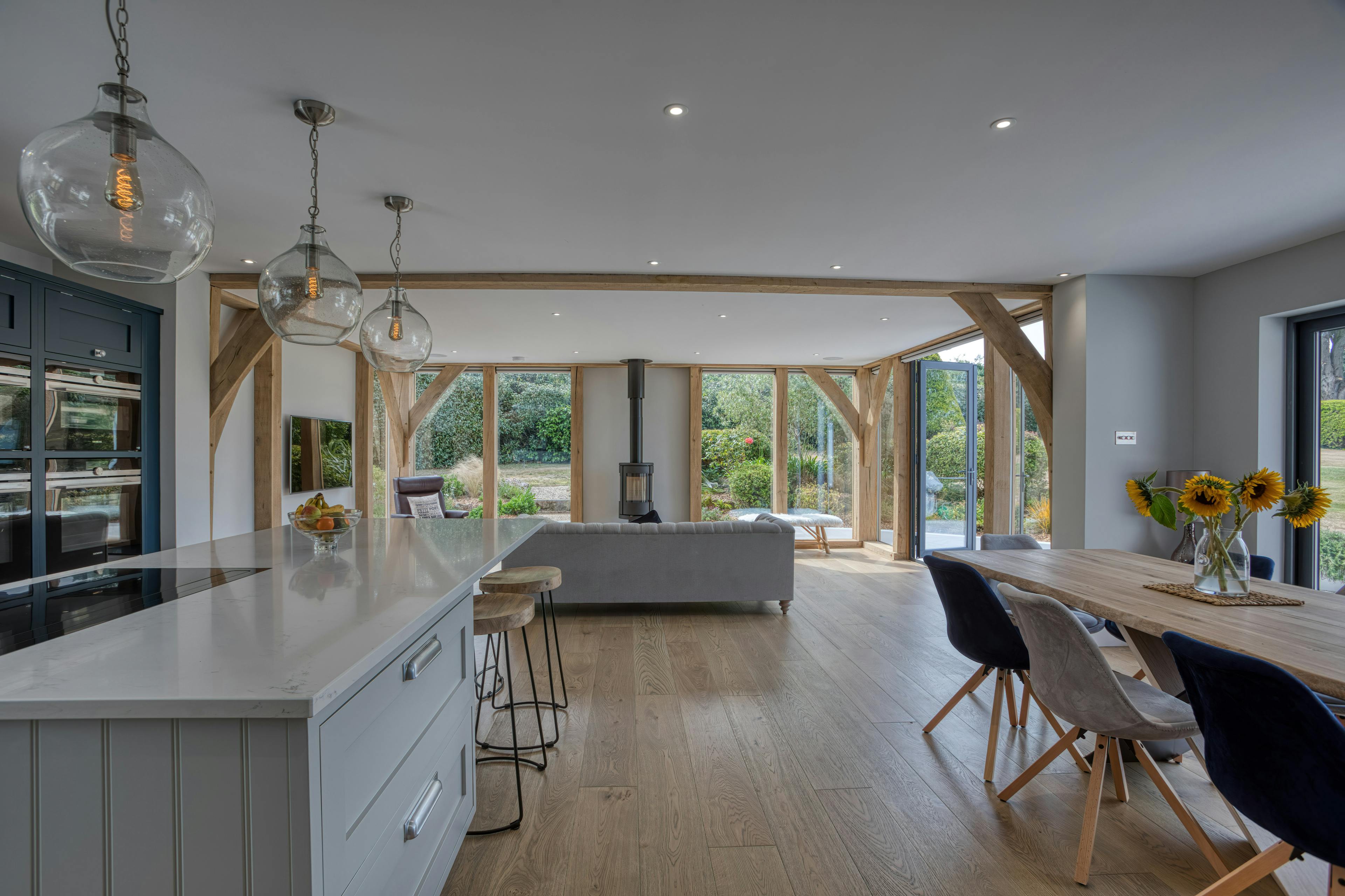 Interior view of an open-plan oak-framed extension with sitting, dining and kitchen areas