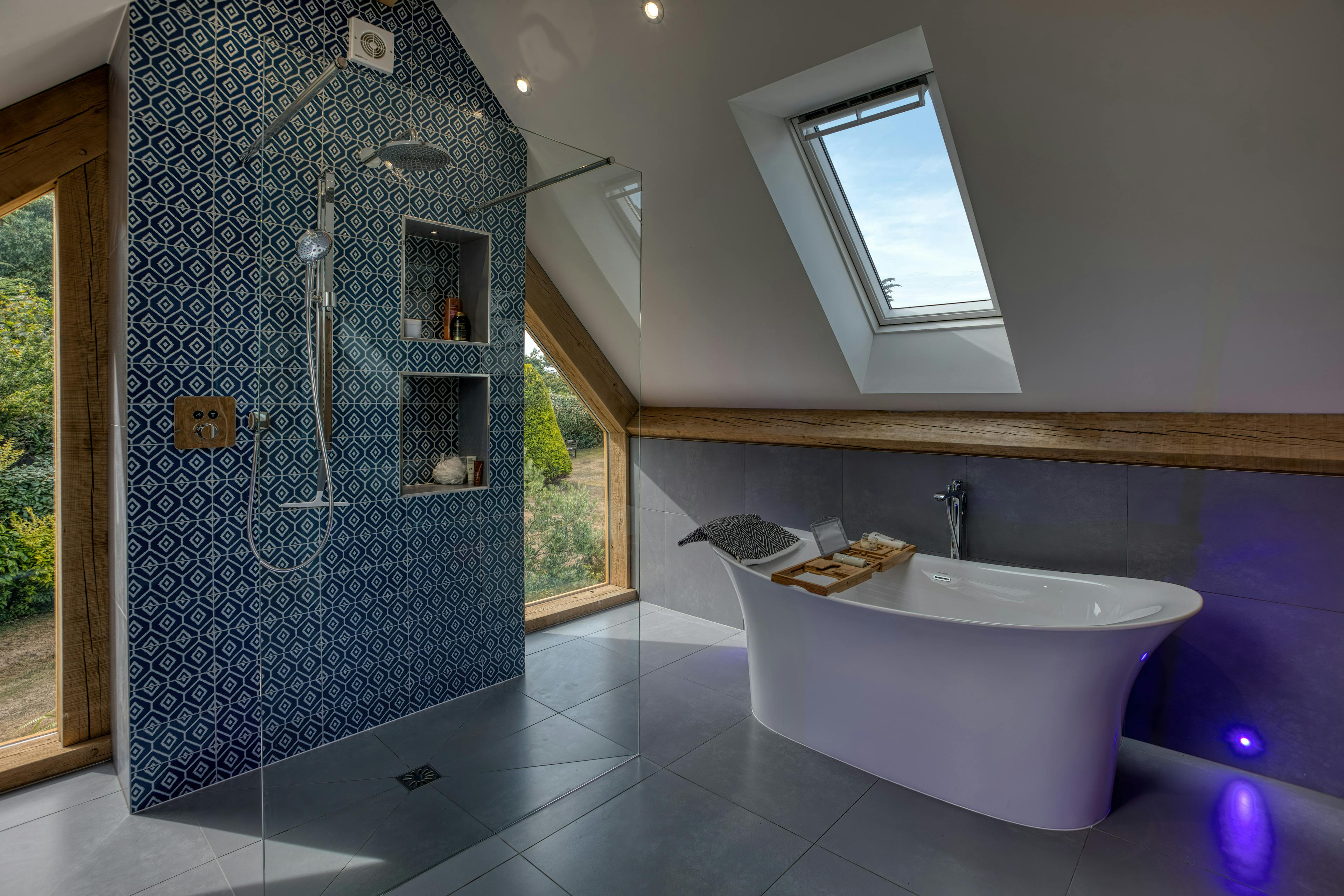 Interior view of a contemporary large bathroom featuring exposed oak-frame beams and a free standing bath