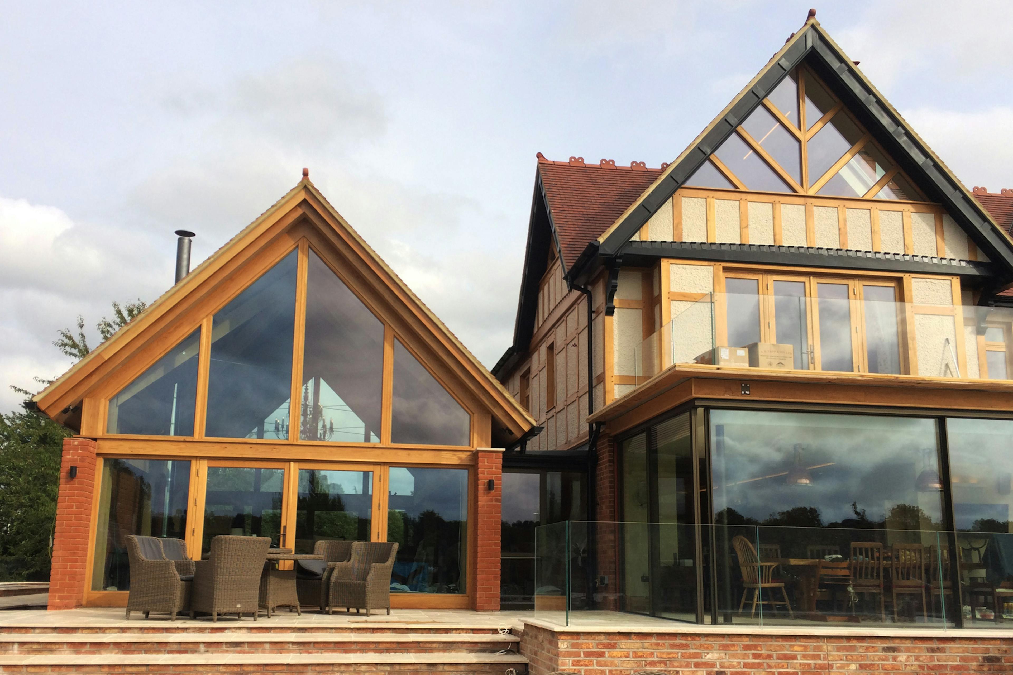 An oak framed extension with a glazed gable end to an arts and craft style house