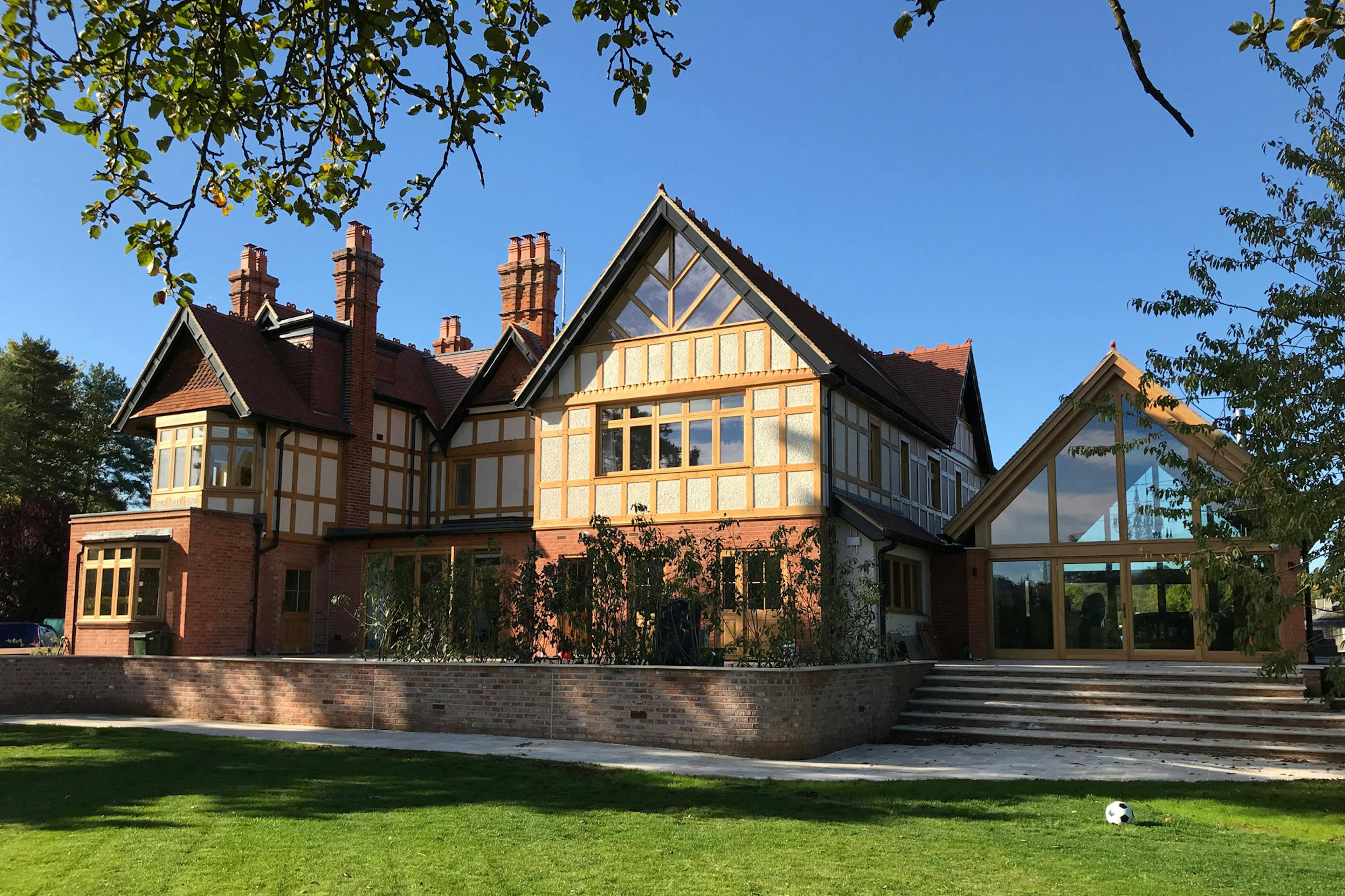 An oak framed extension with a glazed gable end to an arts and craft style house