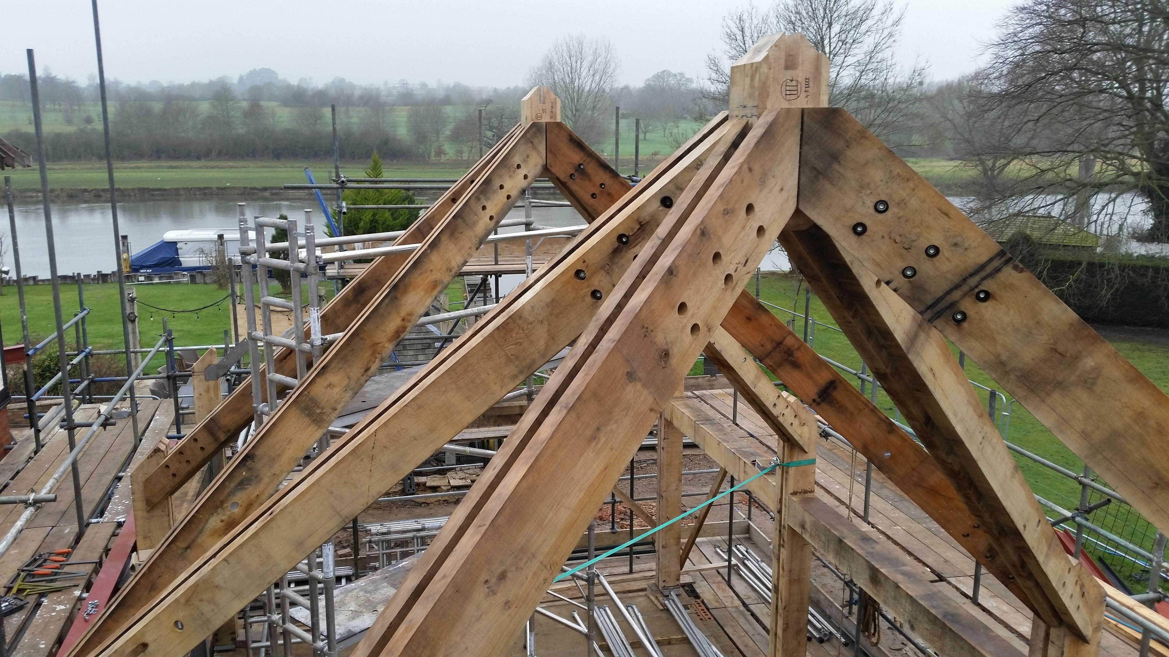 An oak frame with steel connections being installed by a river