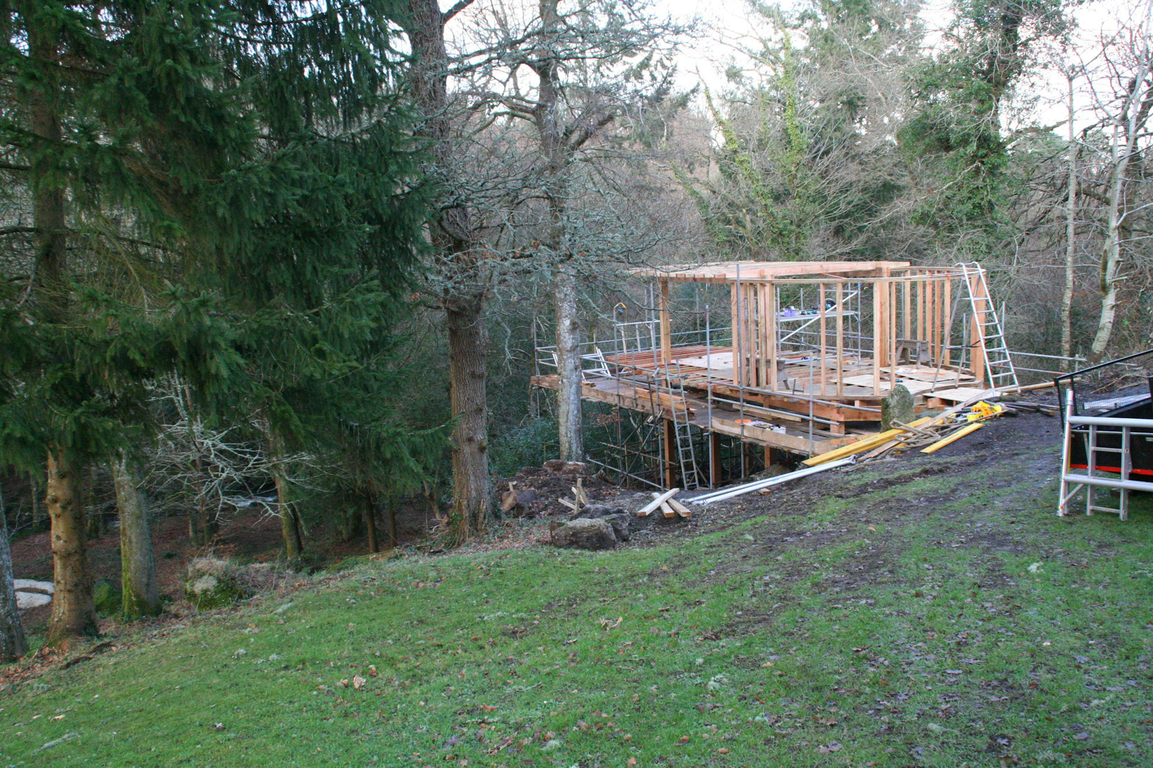 A Douglas fir framed cabin on stilts during construction on a steep sloping site