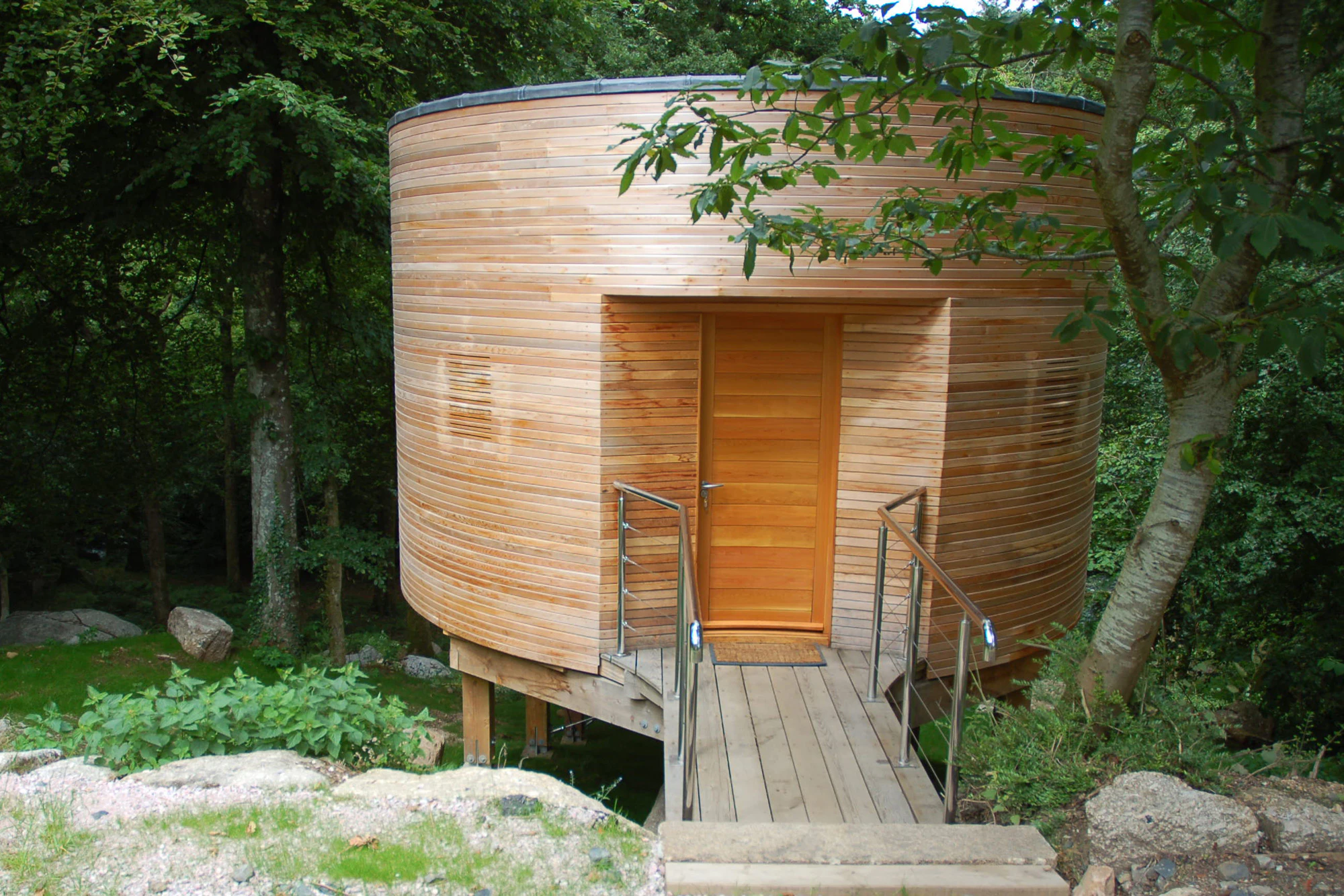 A timber clad Douglas fir framed cabin with a bridge to the entrance door