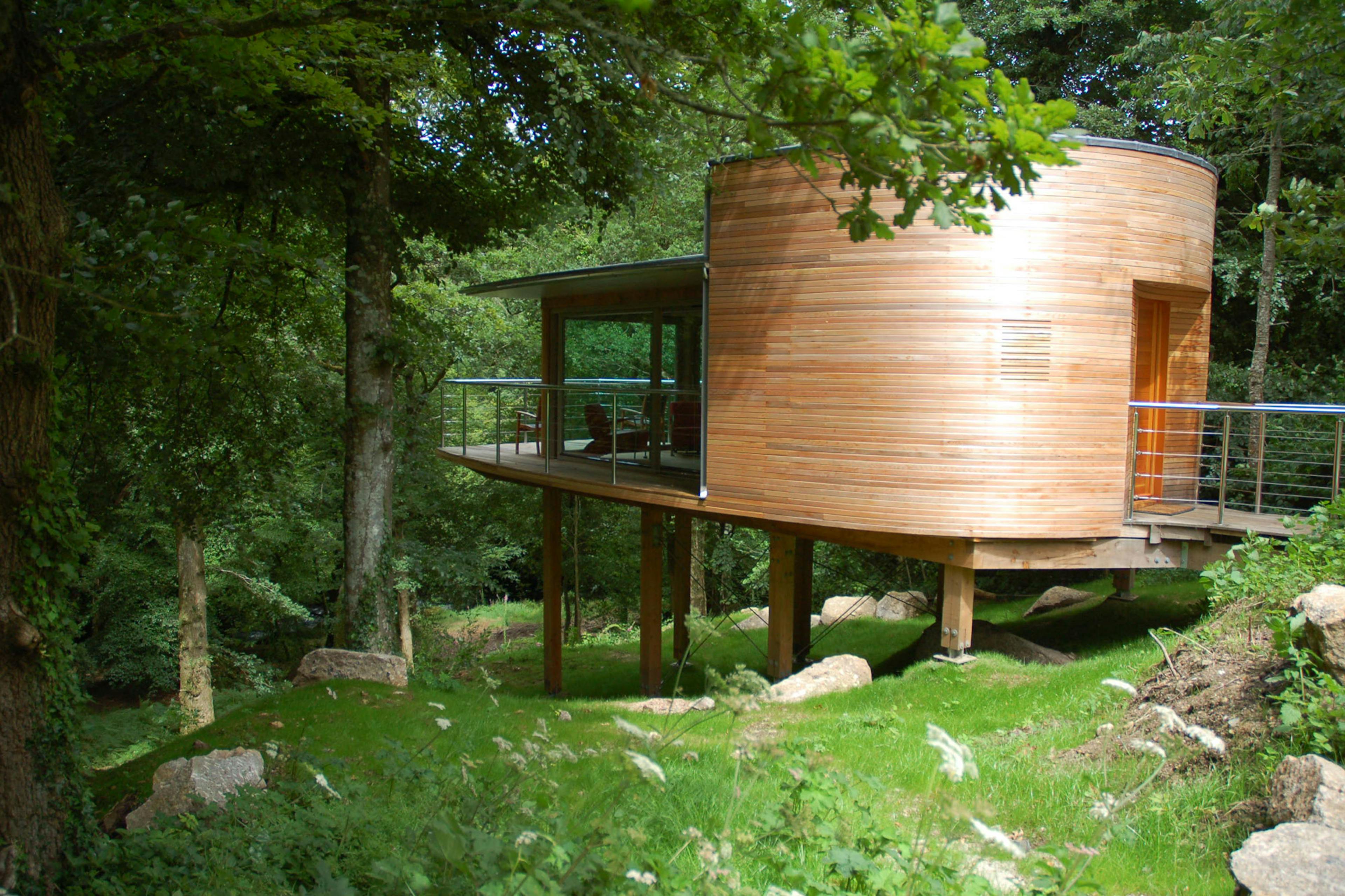 A Douglas fir framed cabin on stilts on a steep green sloping site