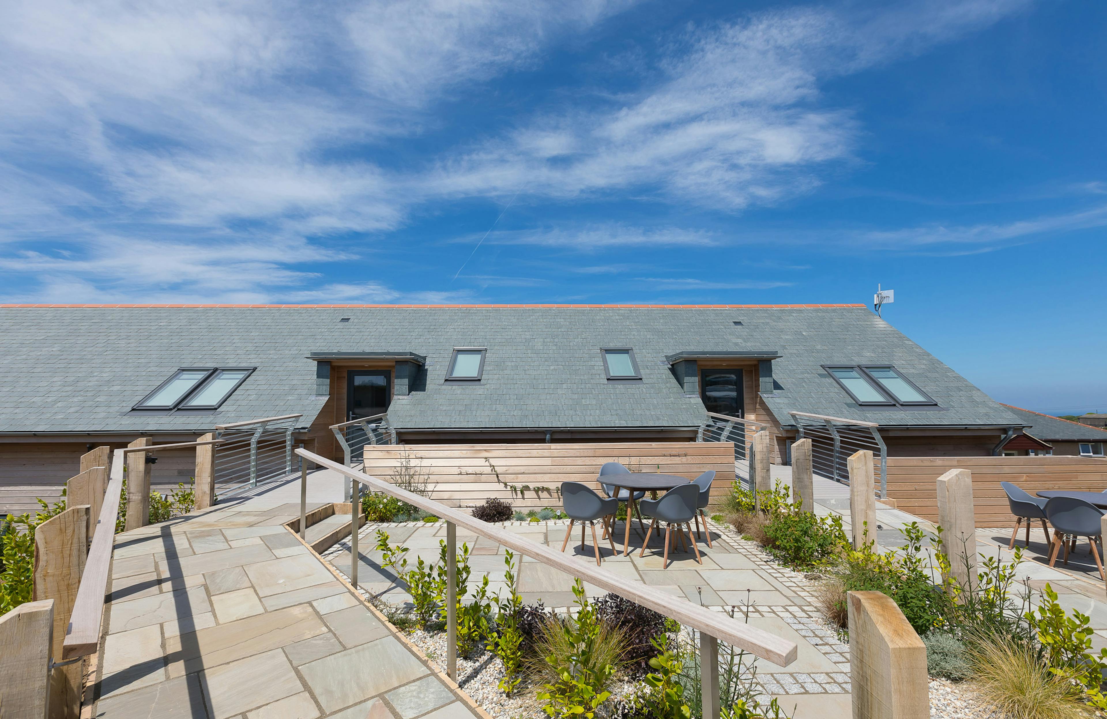 The side of an oak framed building at a caravan park with an exterior patio and outdoor tables and chairs