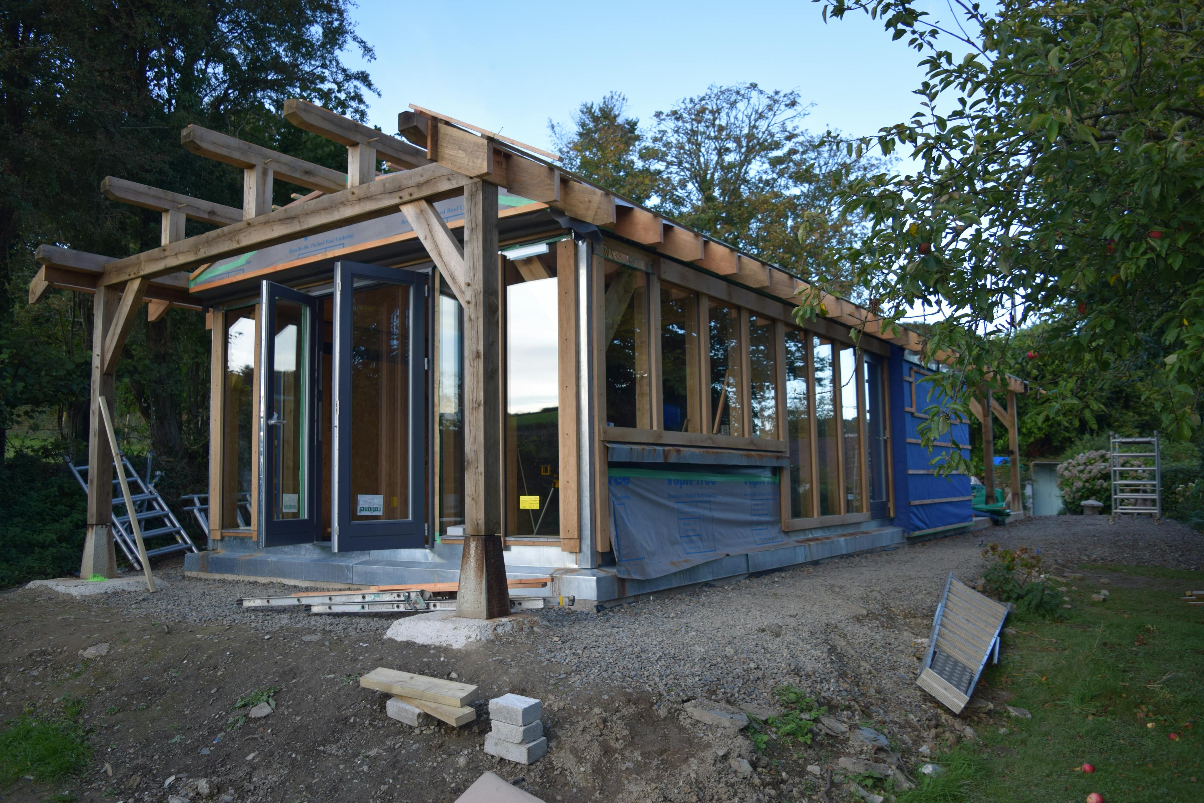 An oak framed cabin during installation with the front glazed doors installed