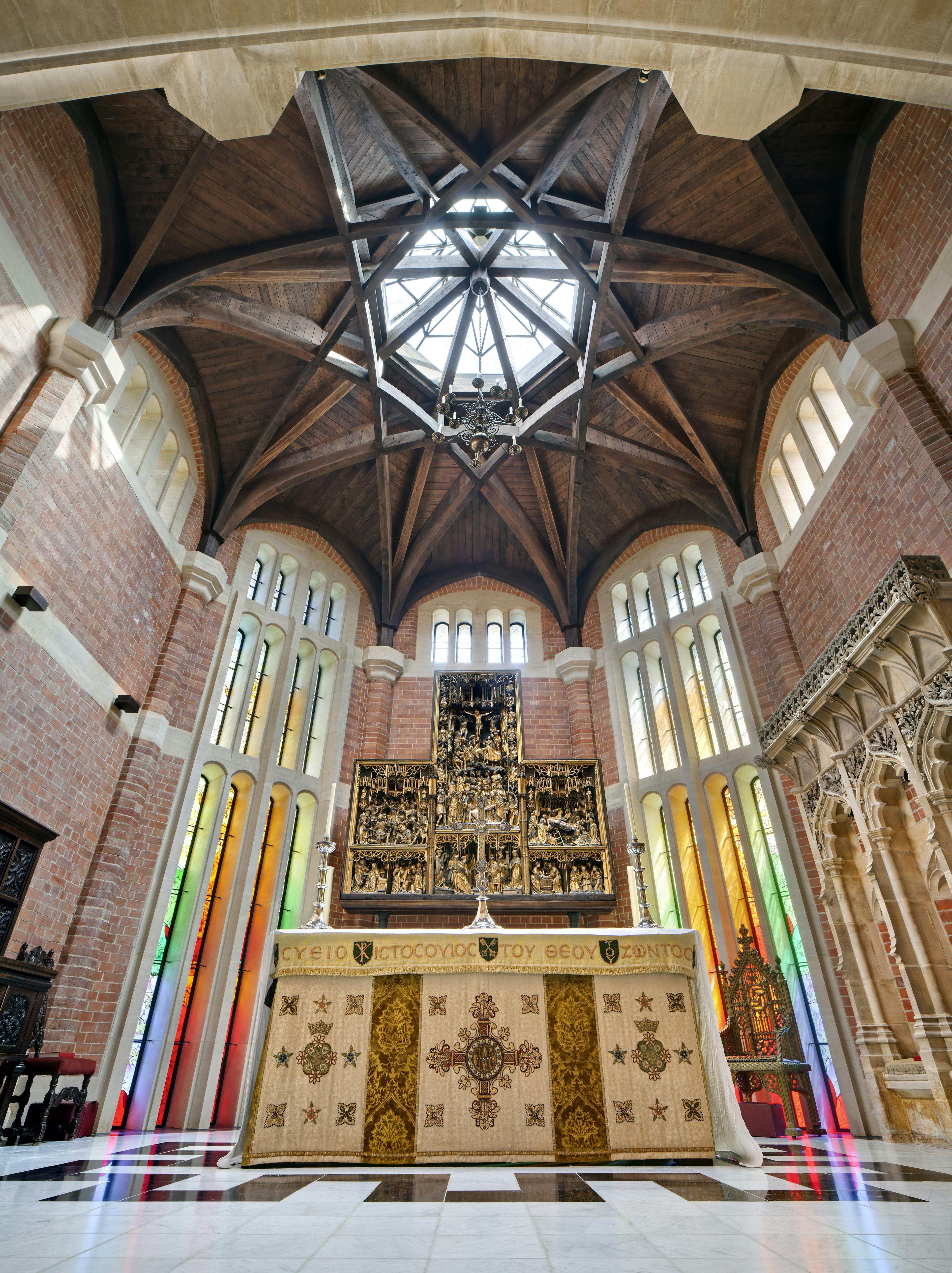 An octagonal oak roof structure in an extension on a chapel with an alter below and stained glass windows