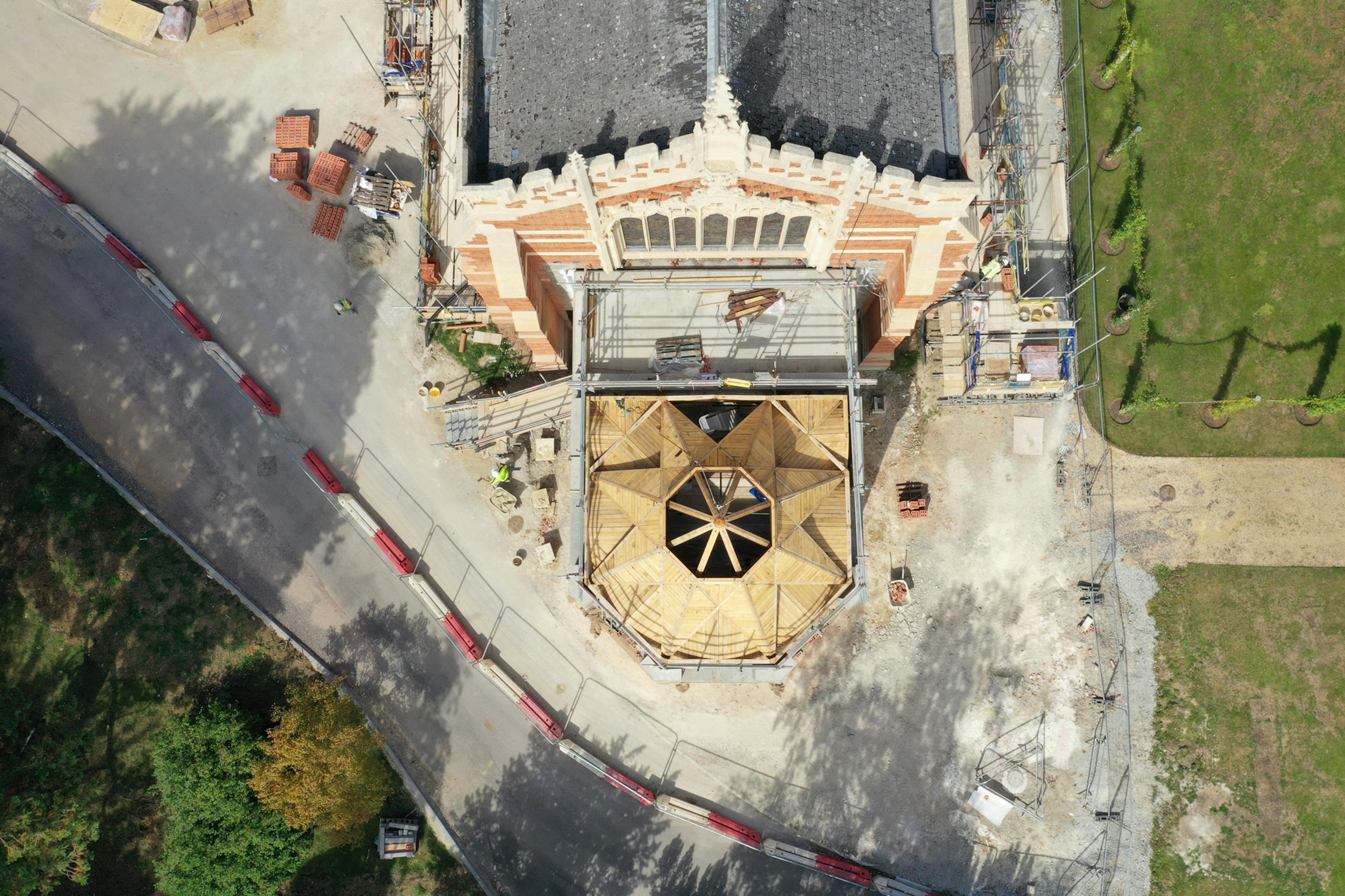 An aerial view of an extension to a 19th century chapel with an octagonal oak framed roof structure during construction 